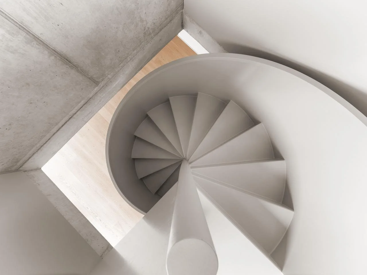 Eine weiße, spiralförmige Wendeltreppe aus Beton oder Stein innerhalb eines minimalistischen, modernen Gebäudes.