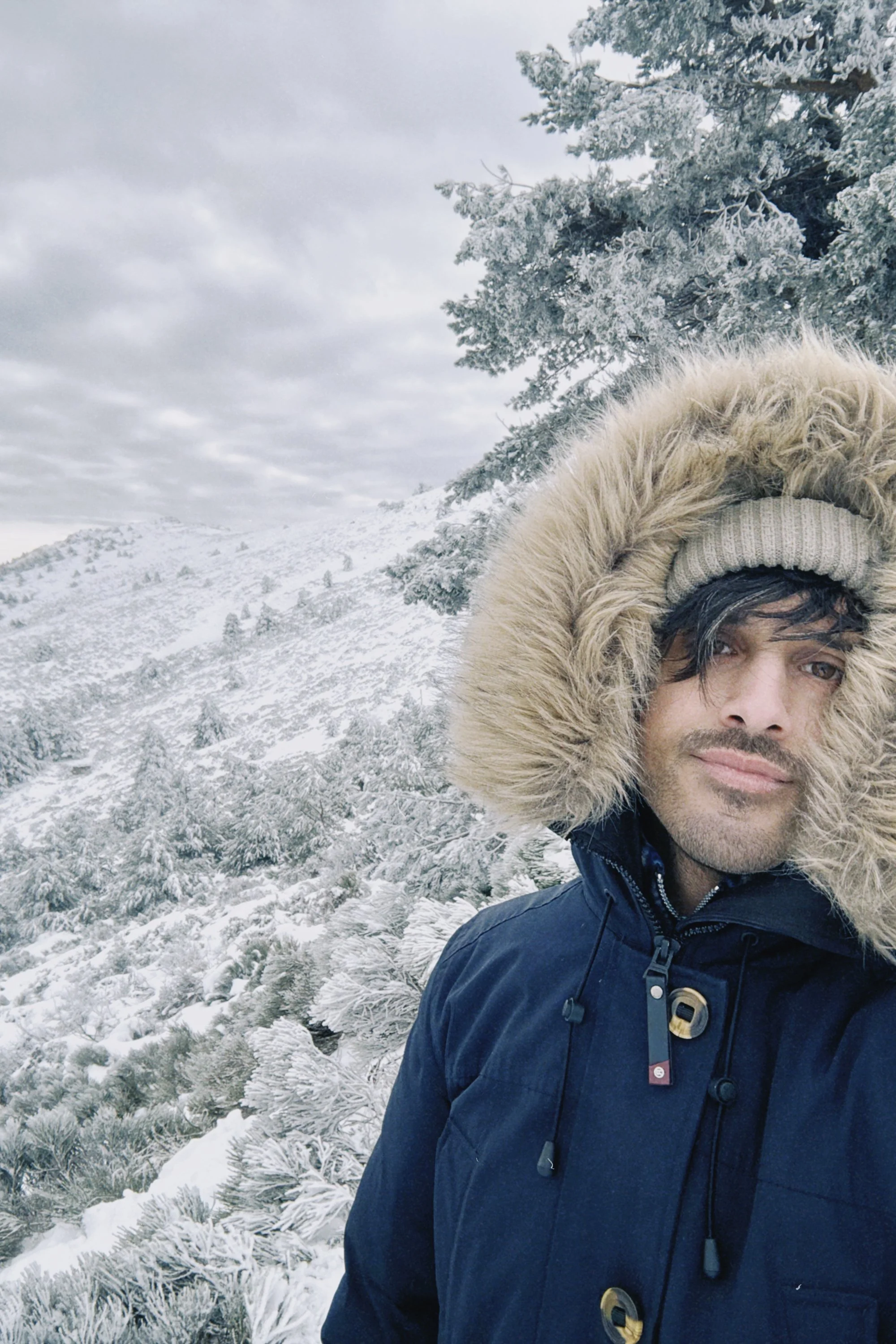 Hombre con abrigo y gorro con piel en un paisaje de montaña nevada