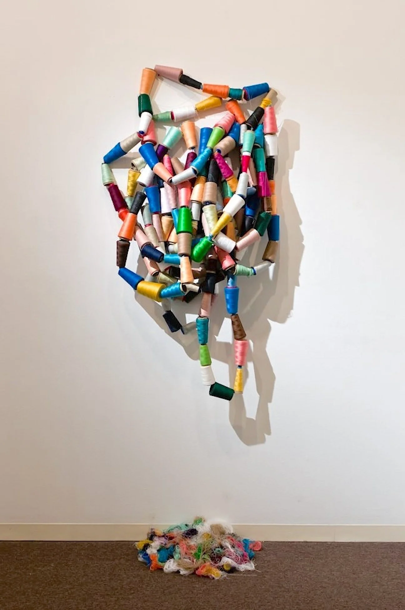 Hanging By A Thread,  48"x20"x10” Discarded industrial sewing machine thread spools, rope