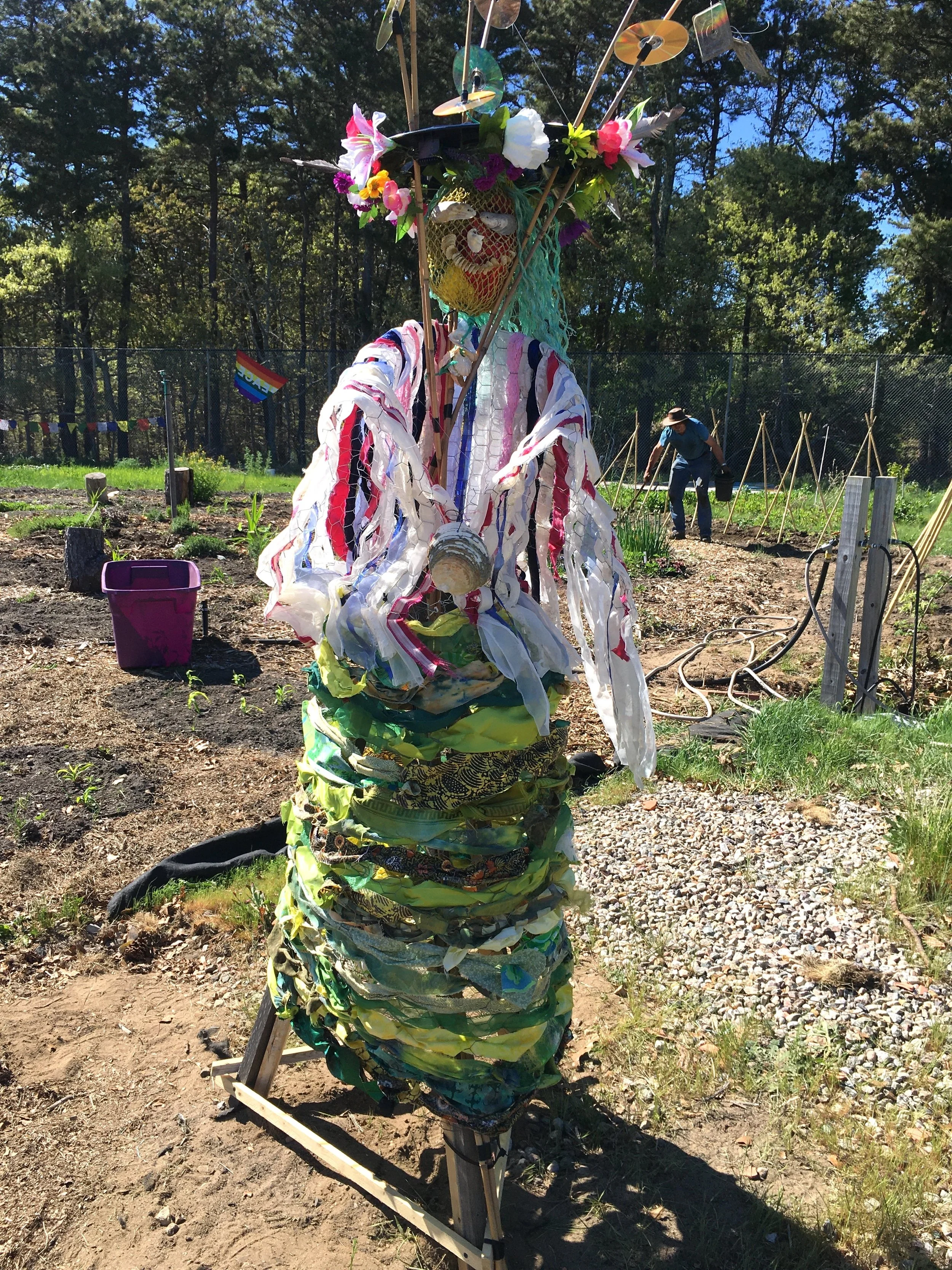 Doreen Mathilde Crow,  72"x24"x24" Fabric, hubcap, silk flowers, CDs, beach detritus, chicken wire, bamboo poles
(Nauset Regional High School Garden, Eastham, MA)