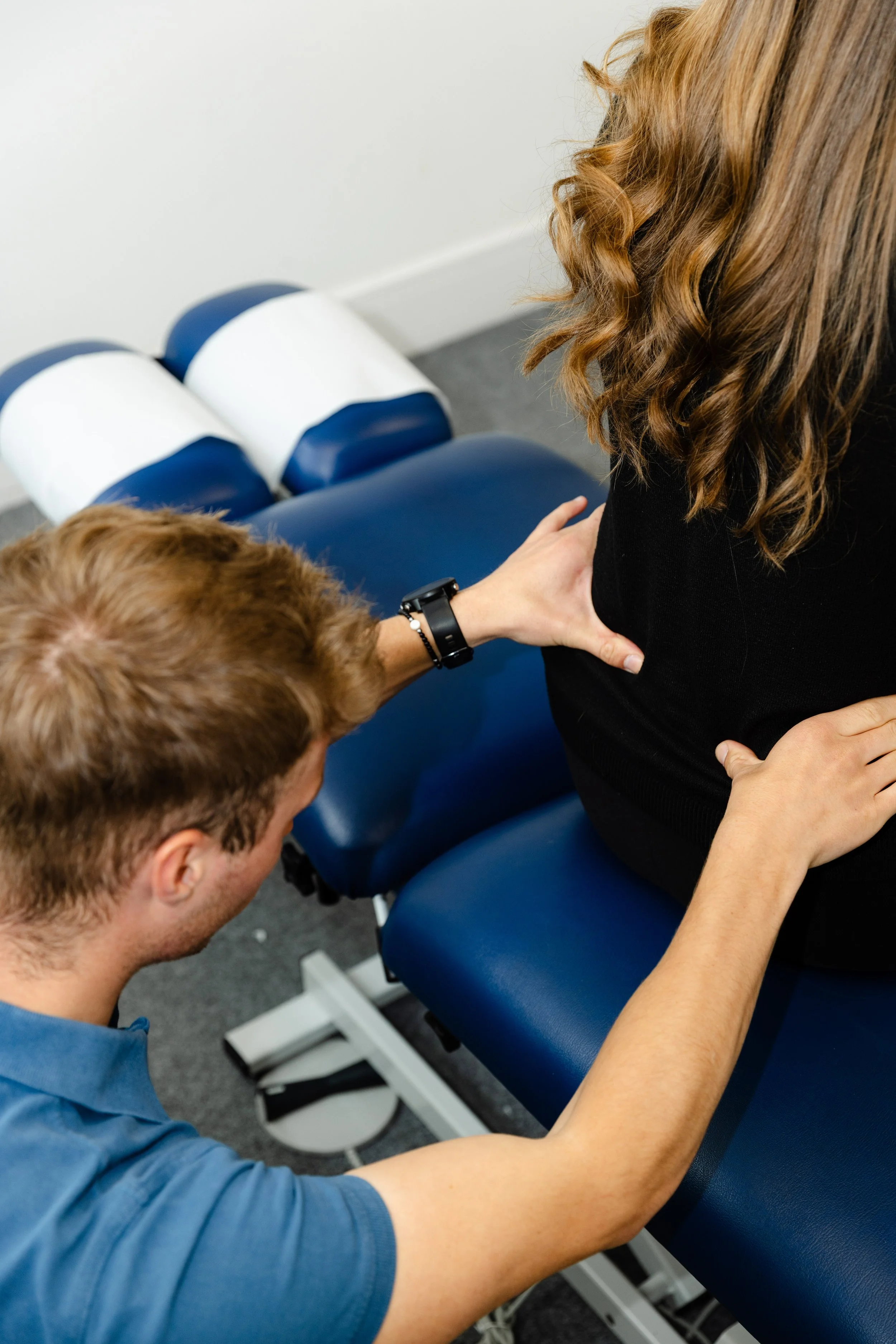 Chiropractor performing an adjustment on a female patient's back in a clinic.