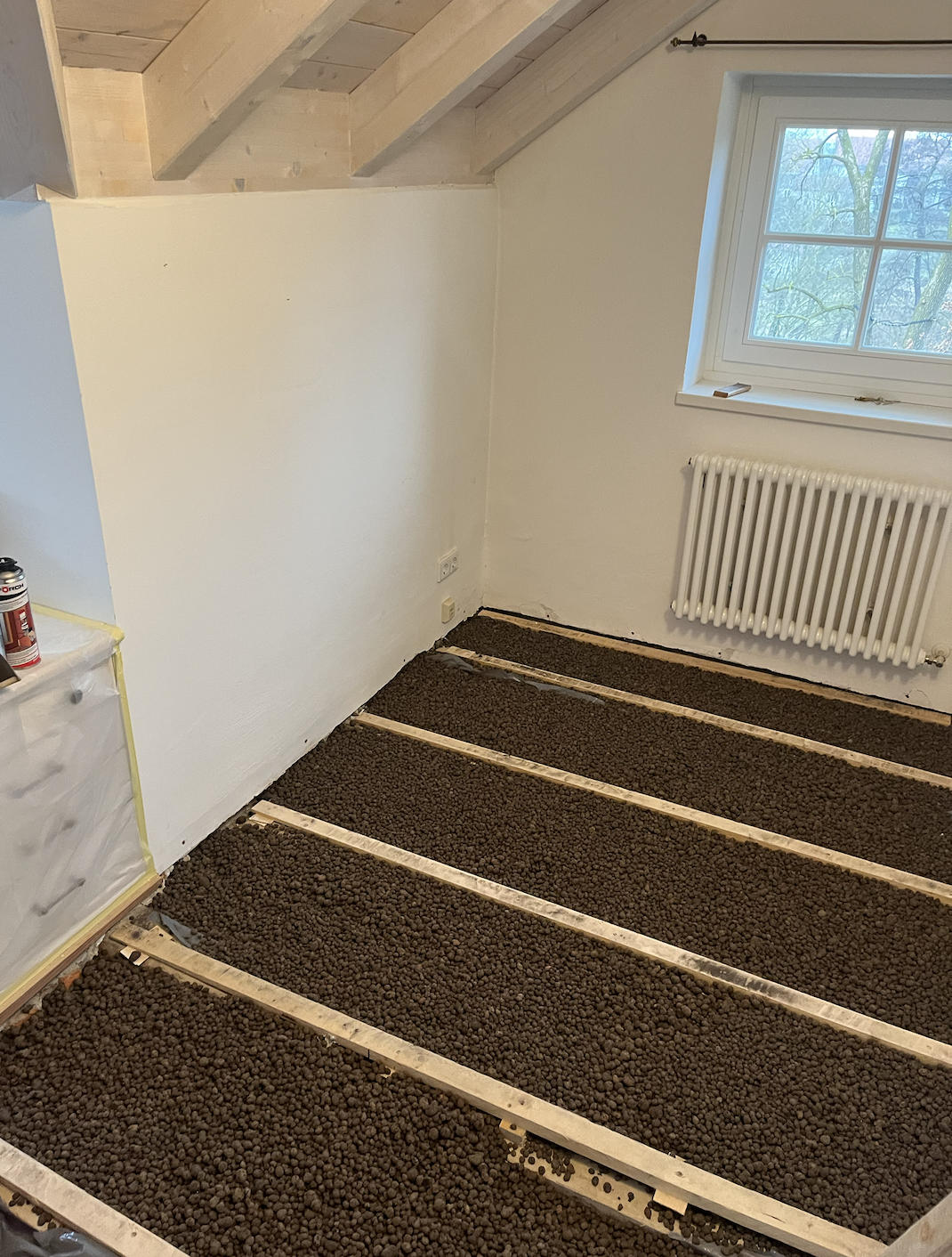Raum mit Fußbodenheizung unter Estrich, Fenster und Heizkörper, frisch renoviert.