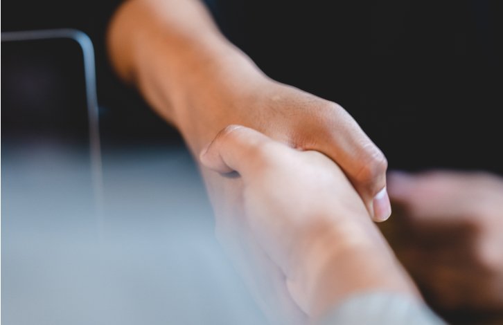 Two people shaking hands with one hand in focus, the background blurred.