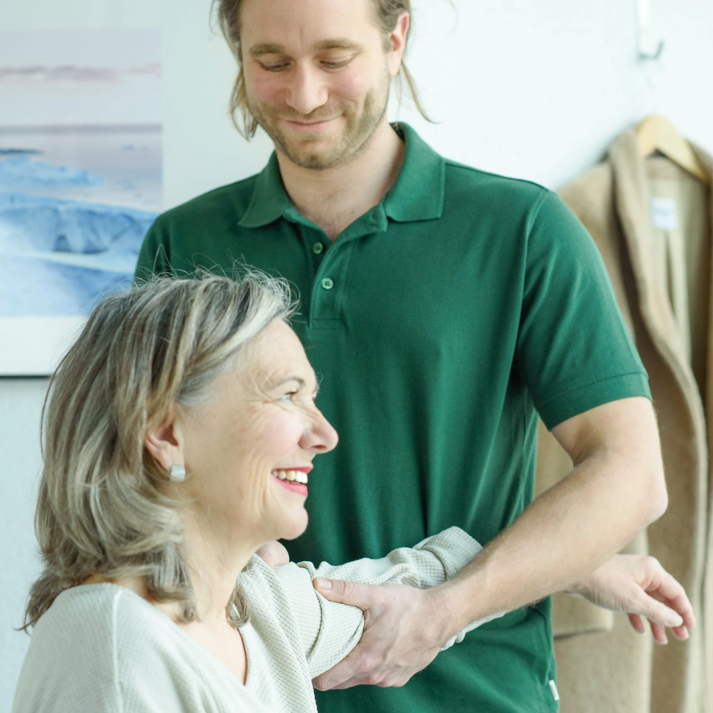 Mann in grüner Poloshirt, der eine Person am Knie behandelt.