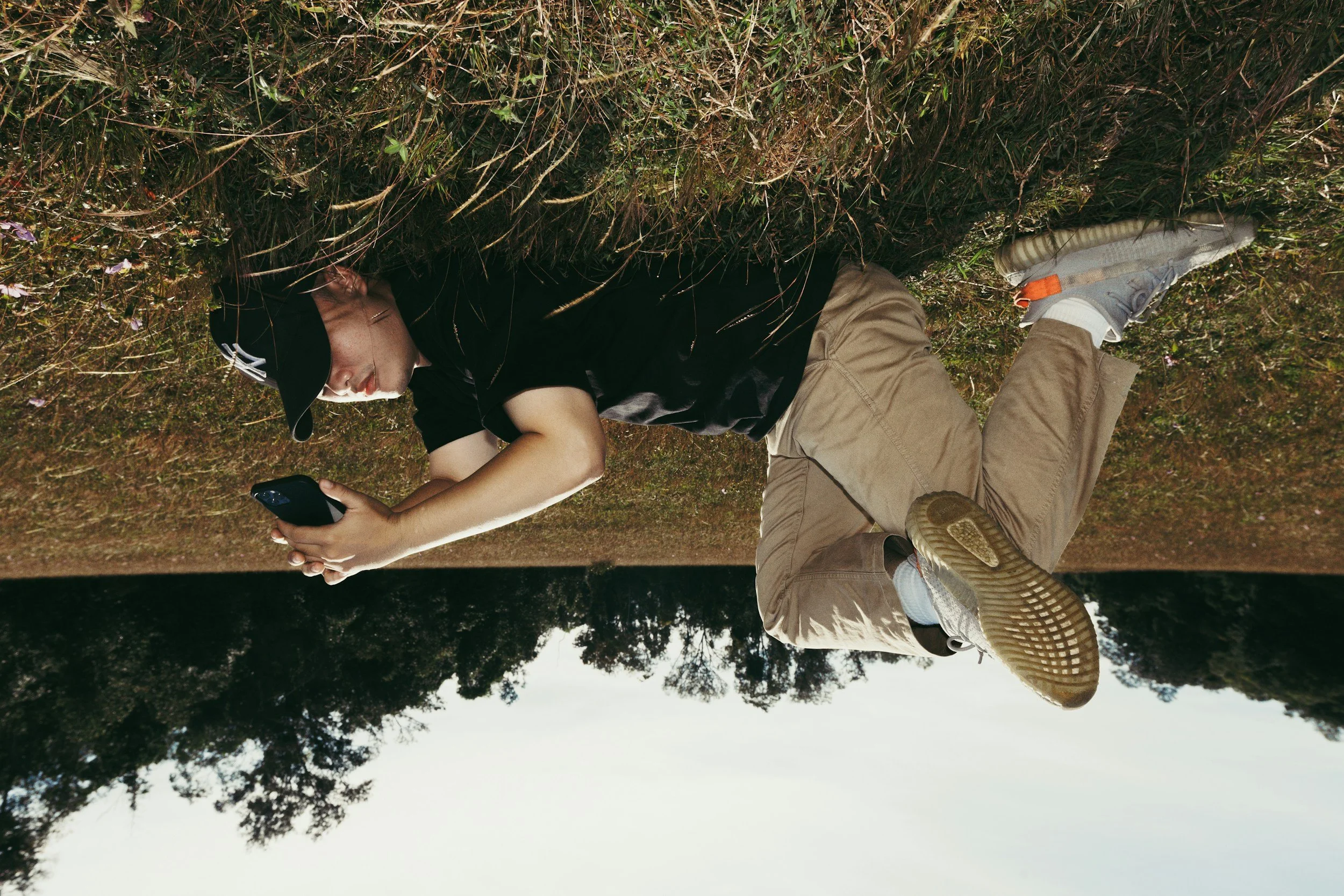 A young man relaxing outside, phone in hand — ready to start his Signal Path interview whenever the moment feels right.