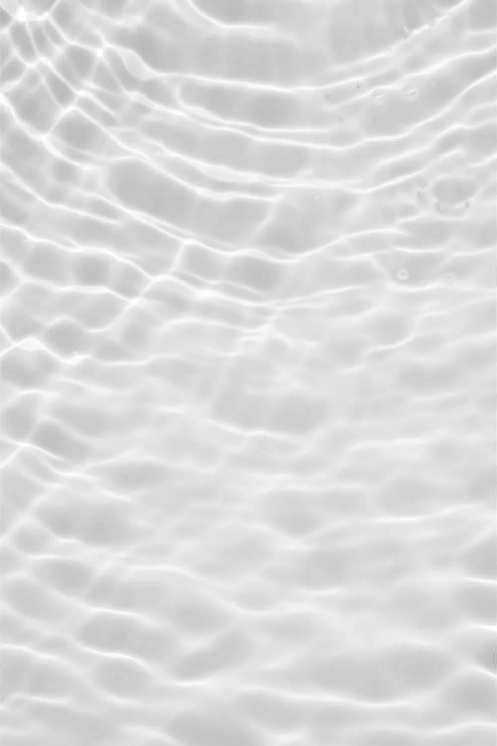 Close-up of clear water with ripples and light reflections.
