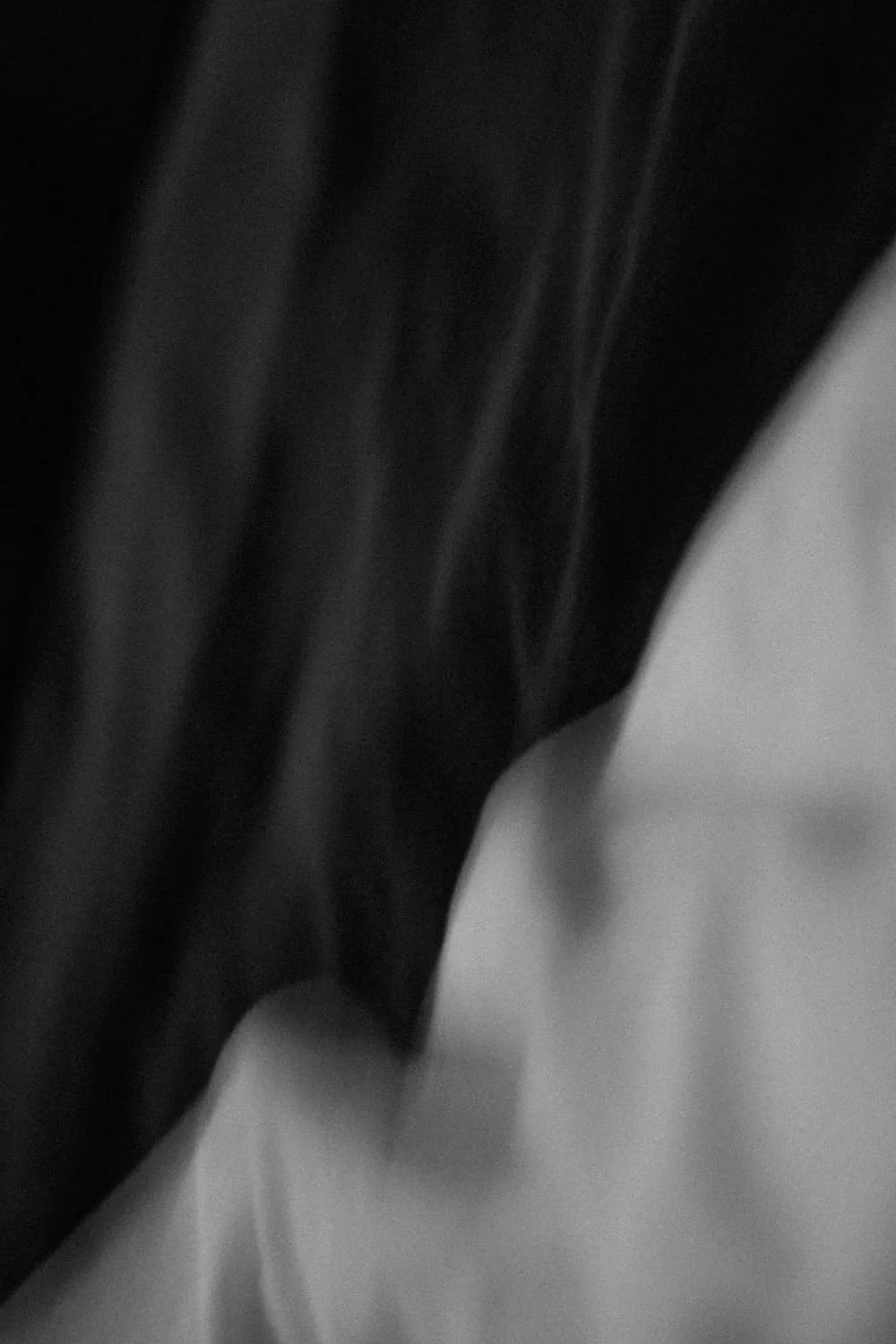 Close-up of black fabric, possibly clothing, with some folds and shadows.