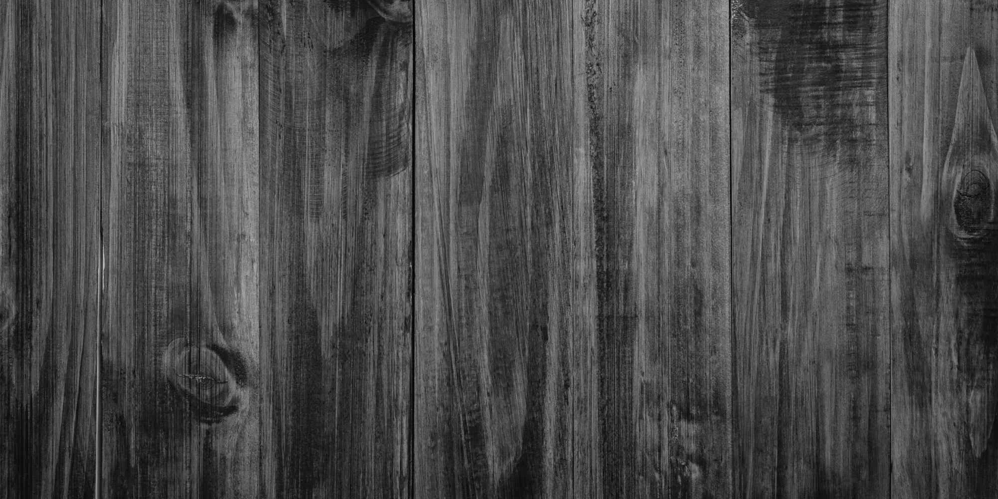 Close-up view of a wooden surface with visible grain and knots, showing a dark textured wood pattern.