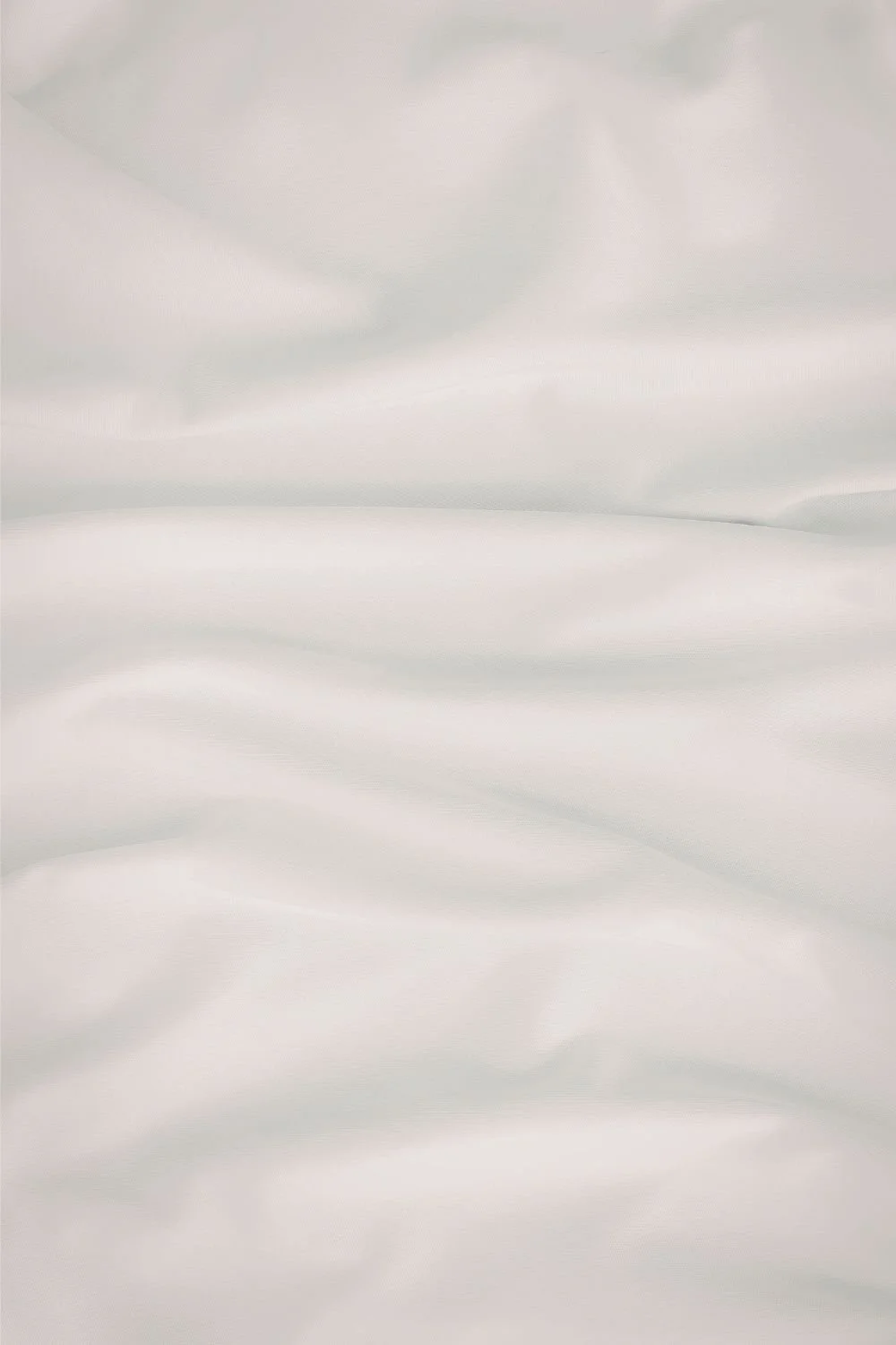 Close-up of smooth, white, textured fabric with gentle folds.