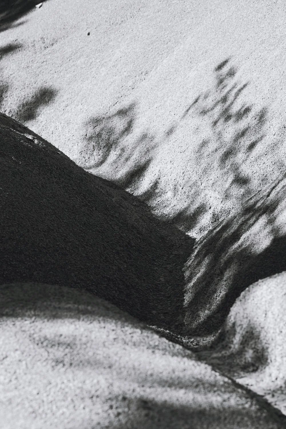 Close-up of a black object surrounded by white powdery substance, possibly adhesive or cement, with textured surface and dust particles.