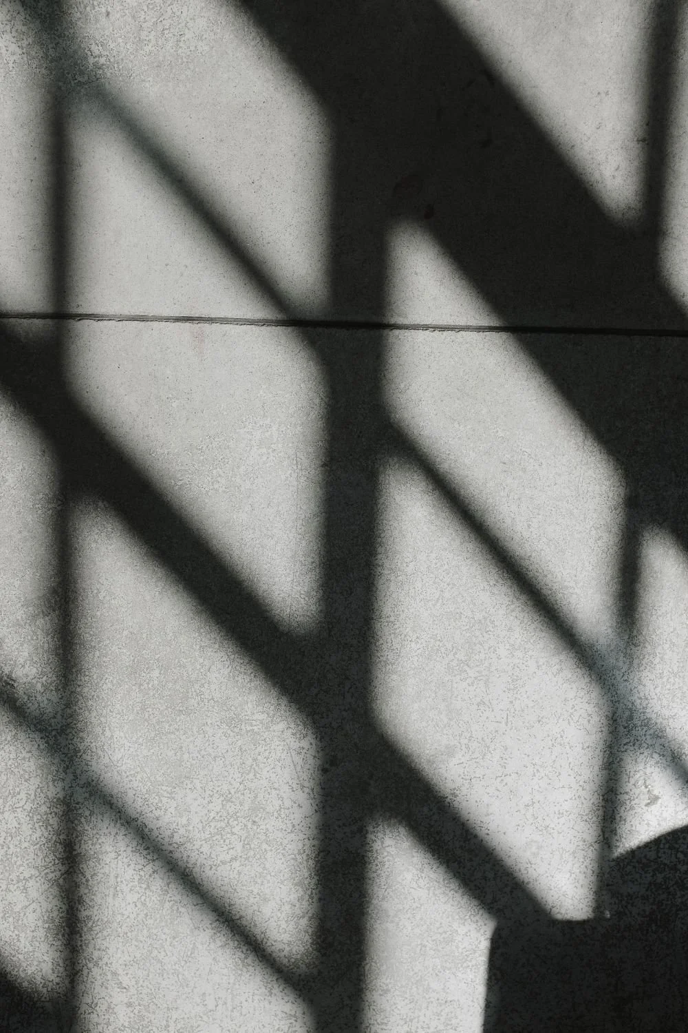 Shadow of a staircase railing on a tiled wall.