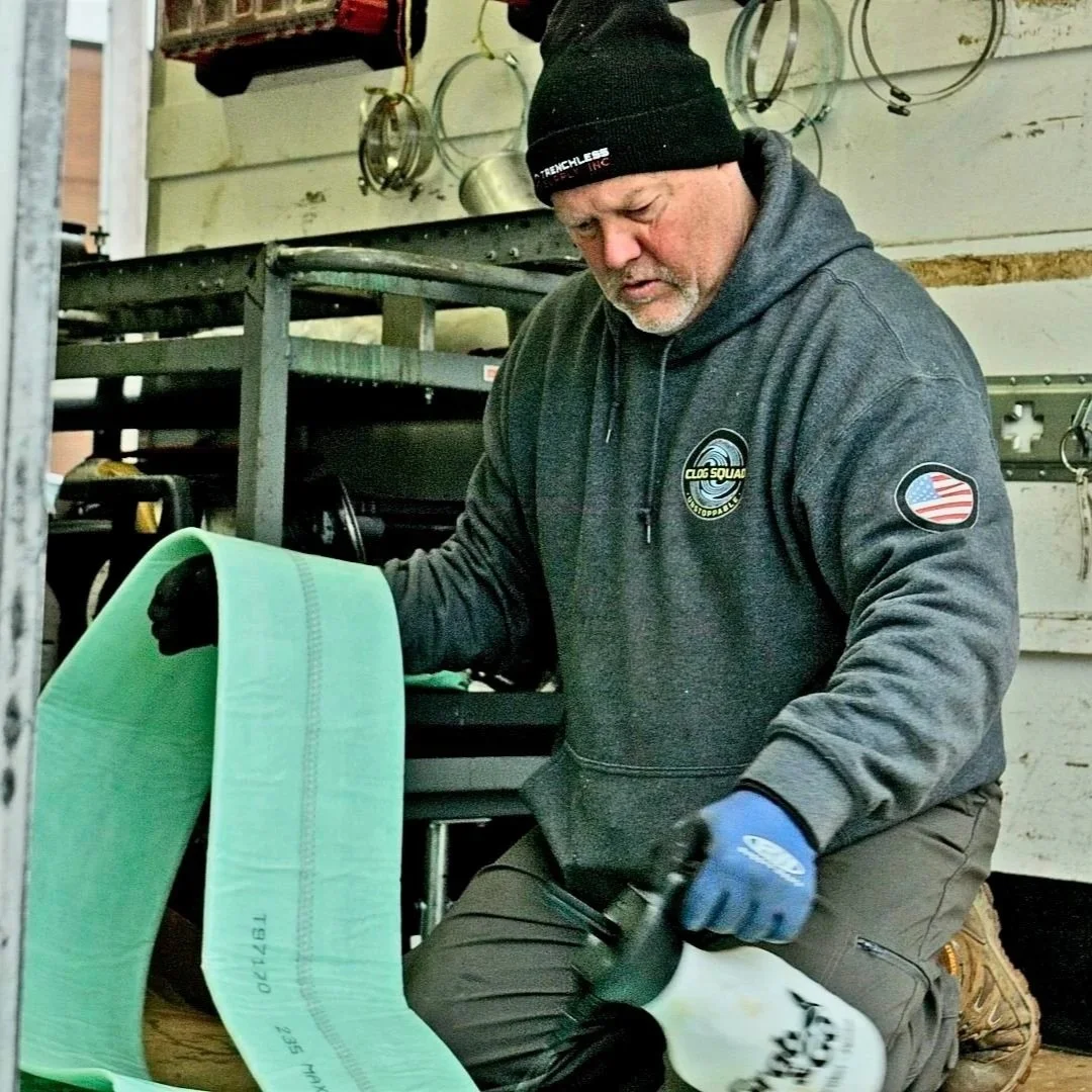 Technician installing green pipe liner inside service truck for trenchless sewer repair.