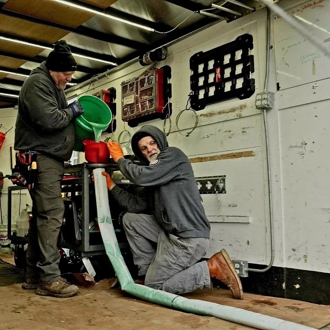 Plumbers conducting routine drain maintenance inside service vehicle.