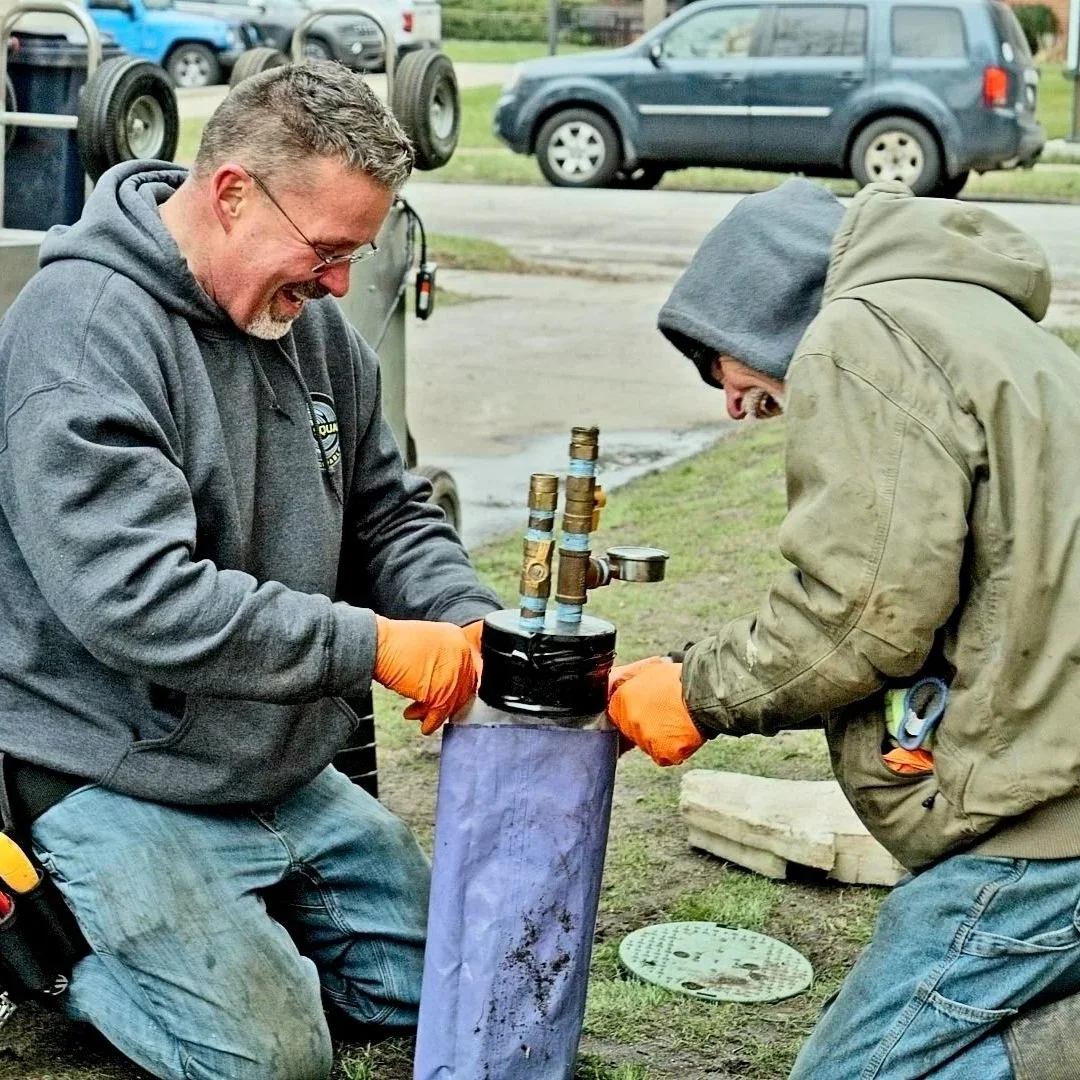Technicians removing tree roots from sewer line using flex-shaft equipment.