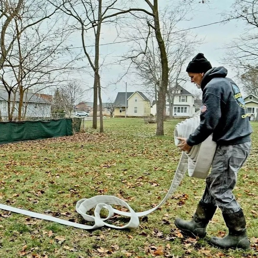 Technician preparing cured-in-place sewer liner installation across residential yard while explaining fifty-year CIPP pipe lifespan and long-term structural durability ratings