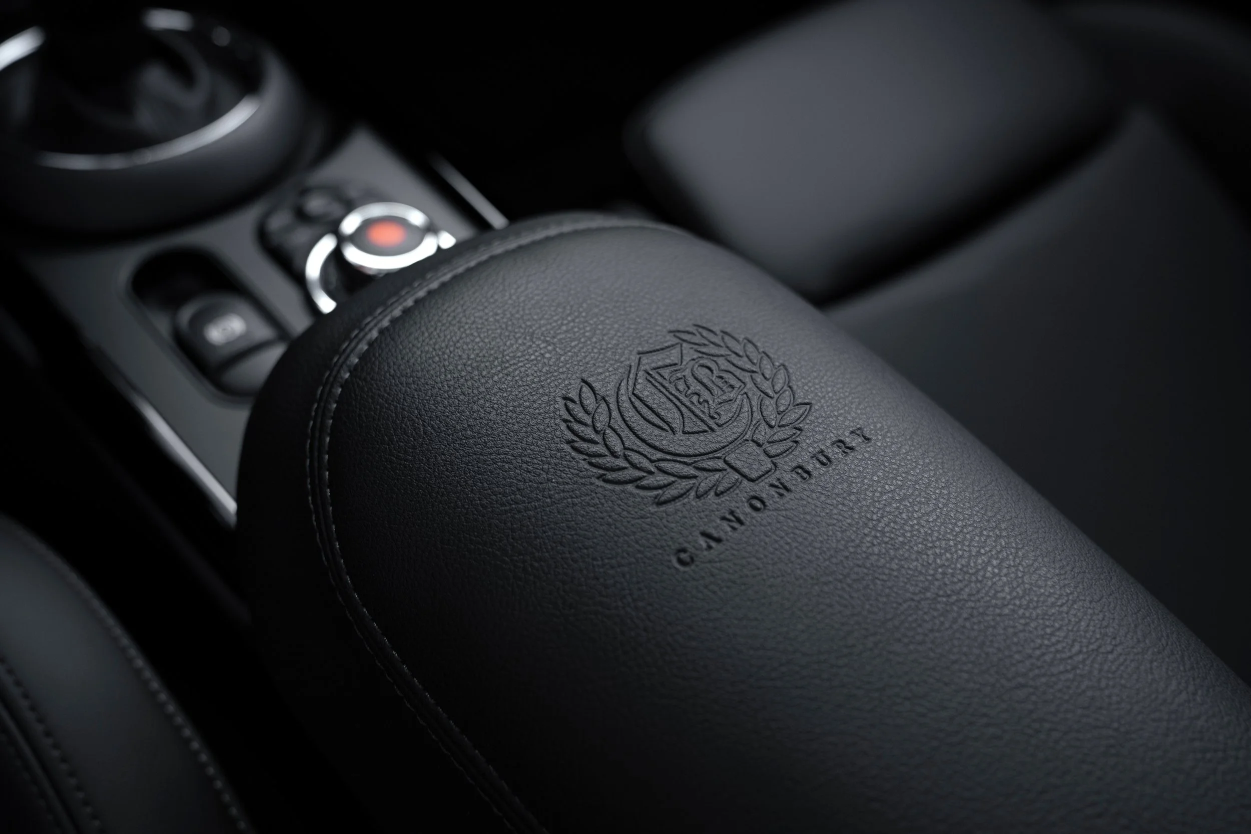 Détail de l'accoudoir central d'une voiture, avec le logo et le nom 'Canterbury' embossés sur le cuir noir.