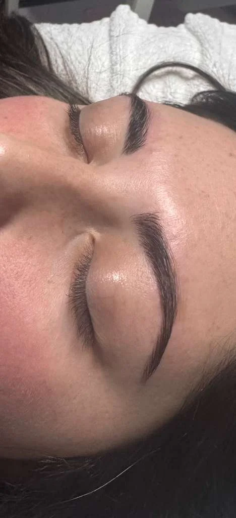 Close-up of a person's face with closed eyes, showing well-groomed eyebrows and smooth skin.