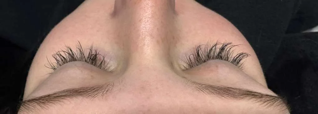 Close-up of person's eyes with long eyelash extensions, upside down view.