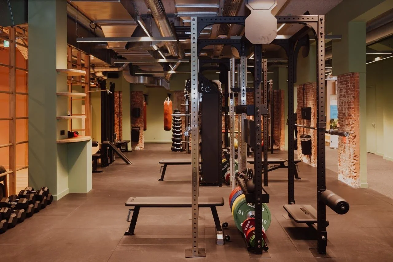 Ein Fitnessstudio mit Kraft- und Ausdauertrainingsgeräten, Hanteln, Langhanteln, Gewichten, einem Kugelhantel.