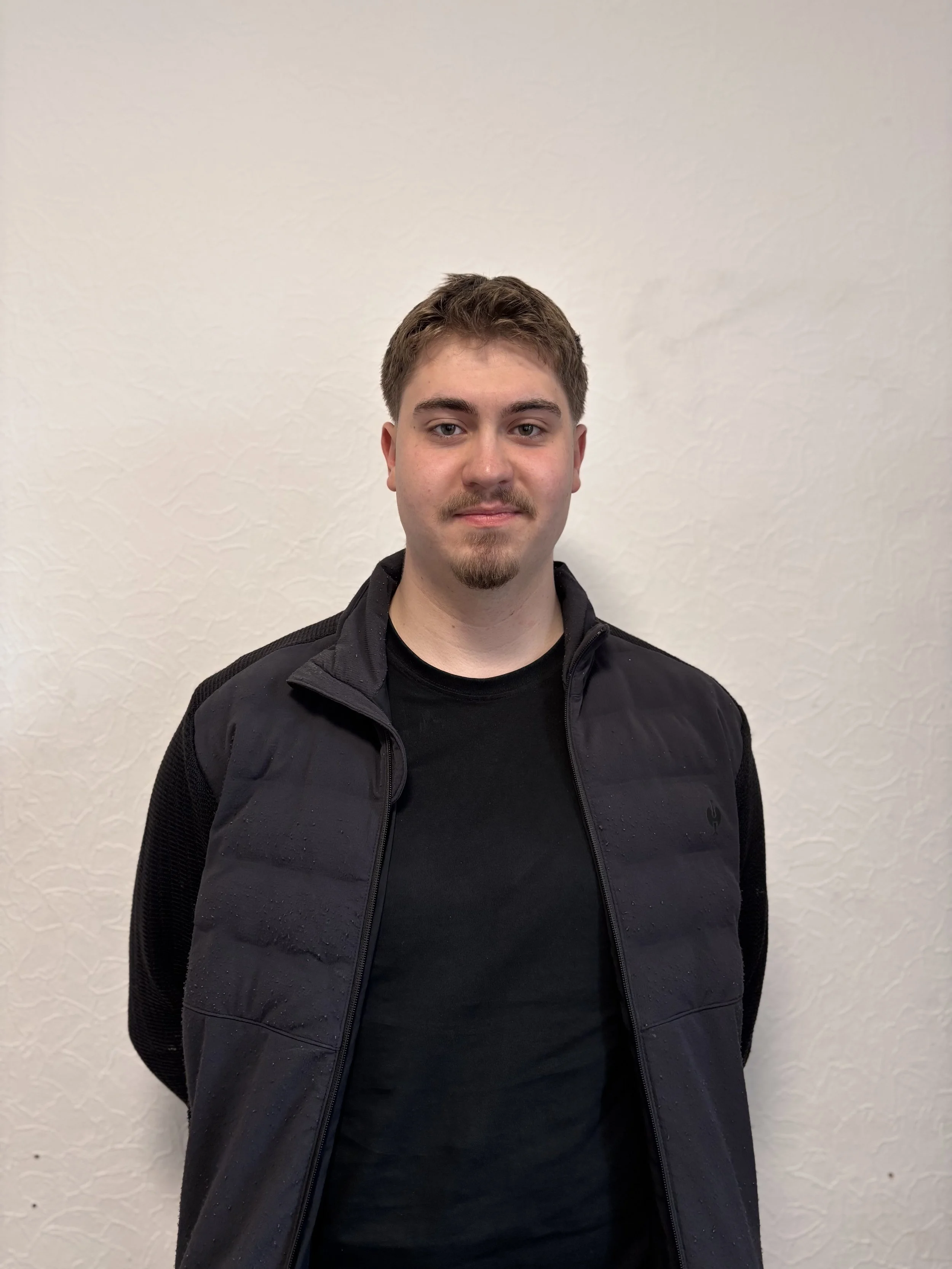 Junger Mann vor einer weißen Wand.