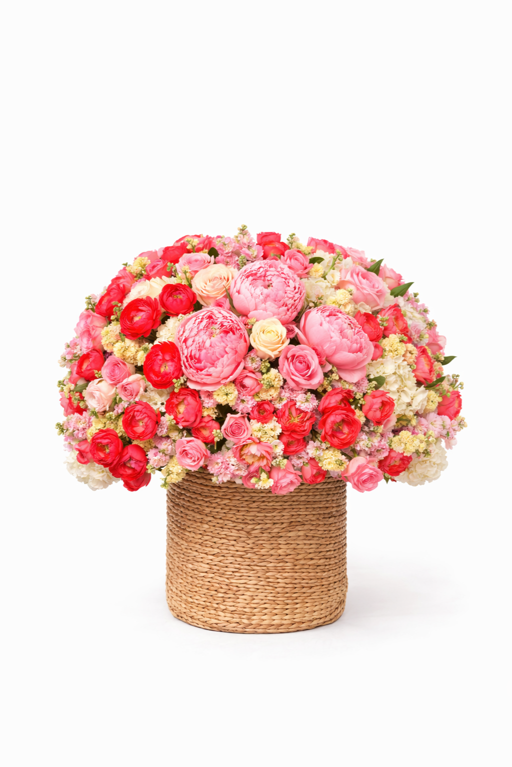 A large bouquet of pink and red flowers in a woven basket against a white background.