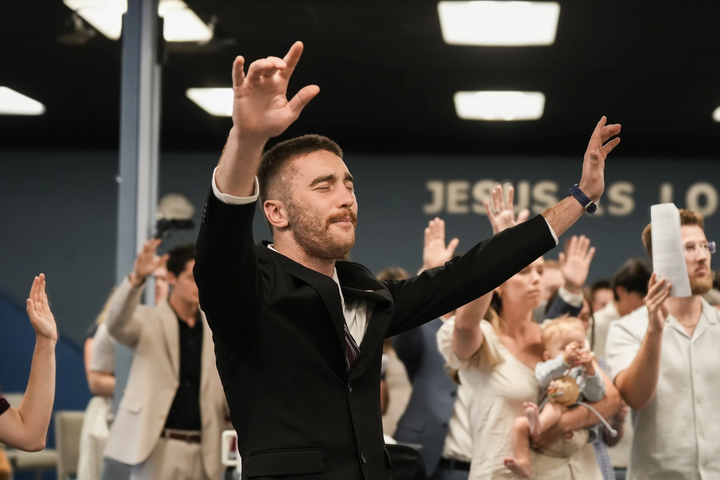 Man and congregation worshipping with hands lifted