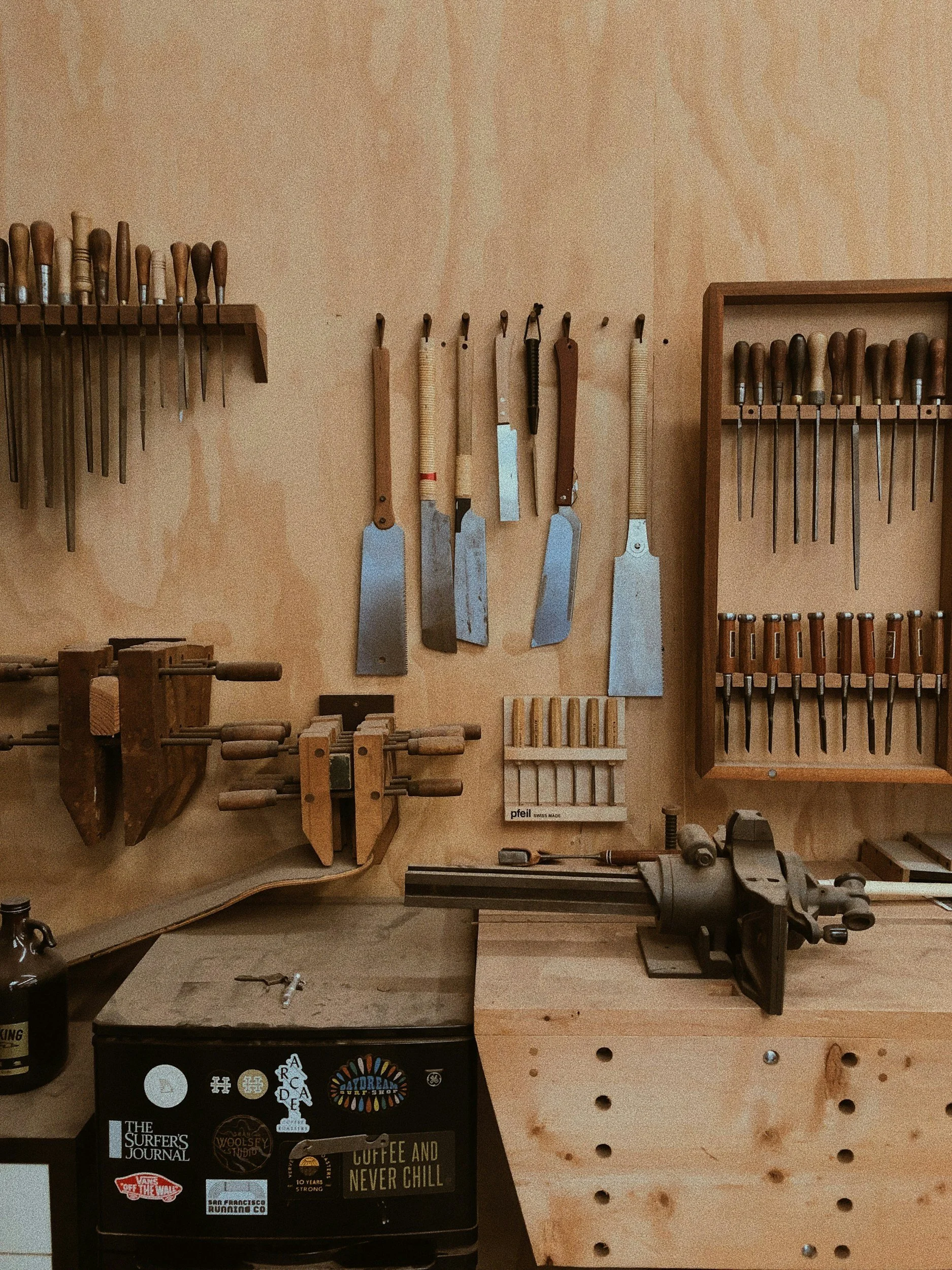 Tools on a wooden wall, including chisels and clamps, in a woodworking workshop.
