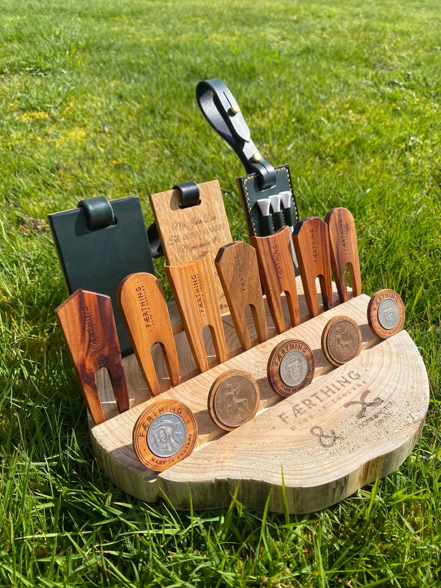 Wooden and leather gardening tools set with engraved handles, displayed on a wooden tray outdoors on grass.