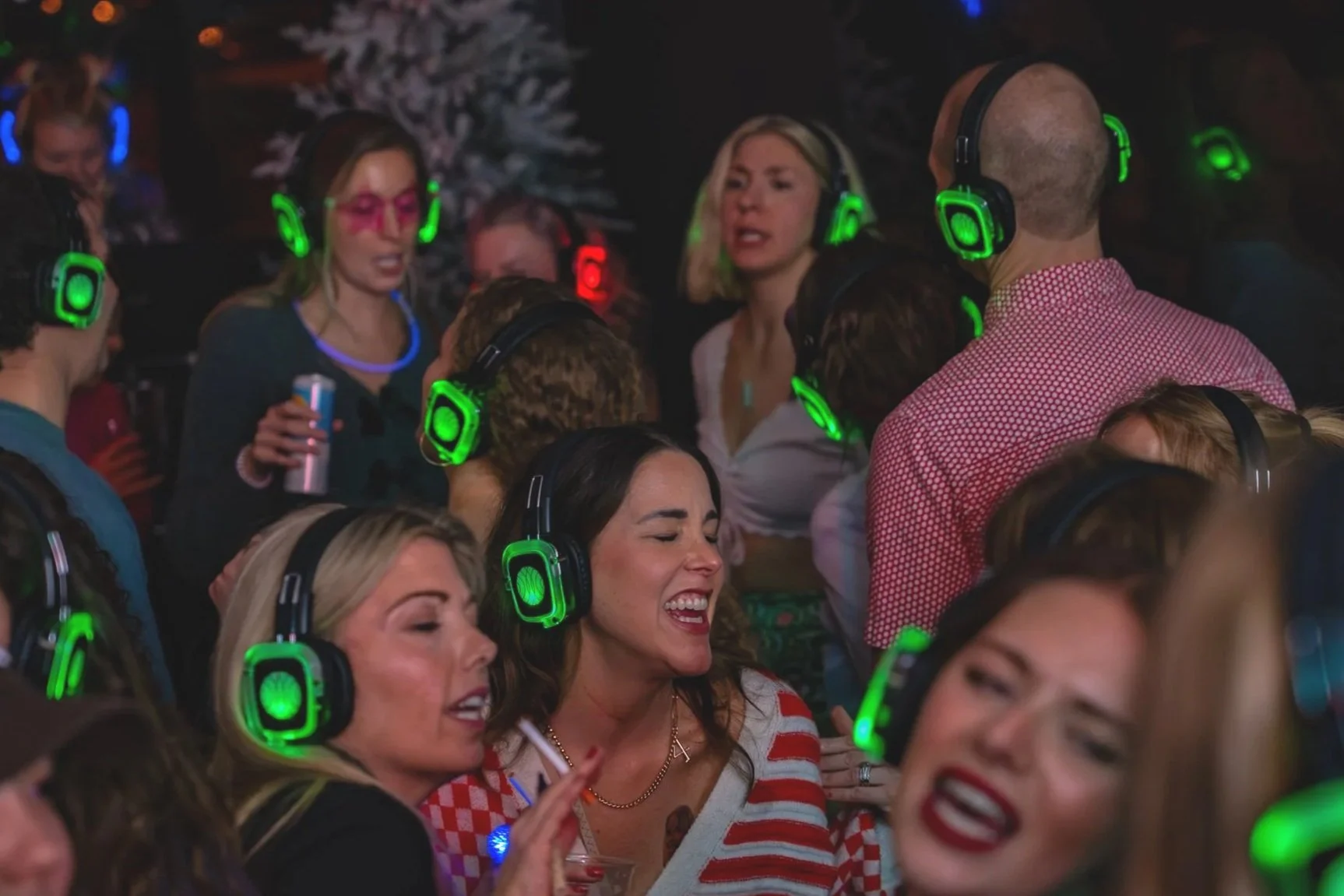 Group of people wearing headphones and singing or dancing at a party or karaoke event.