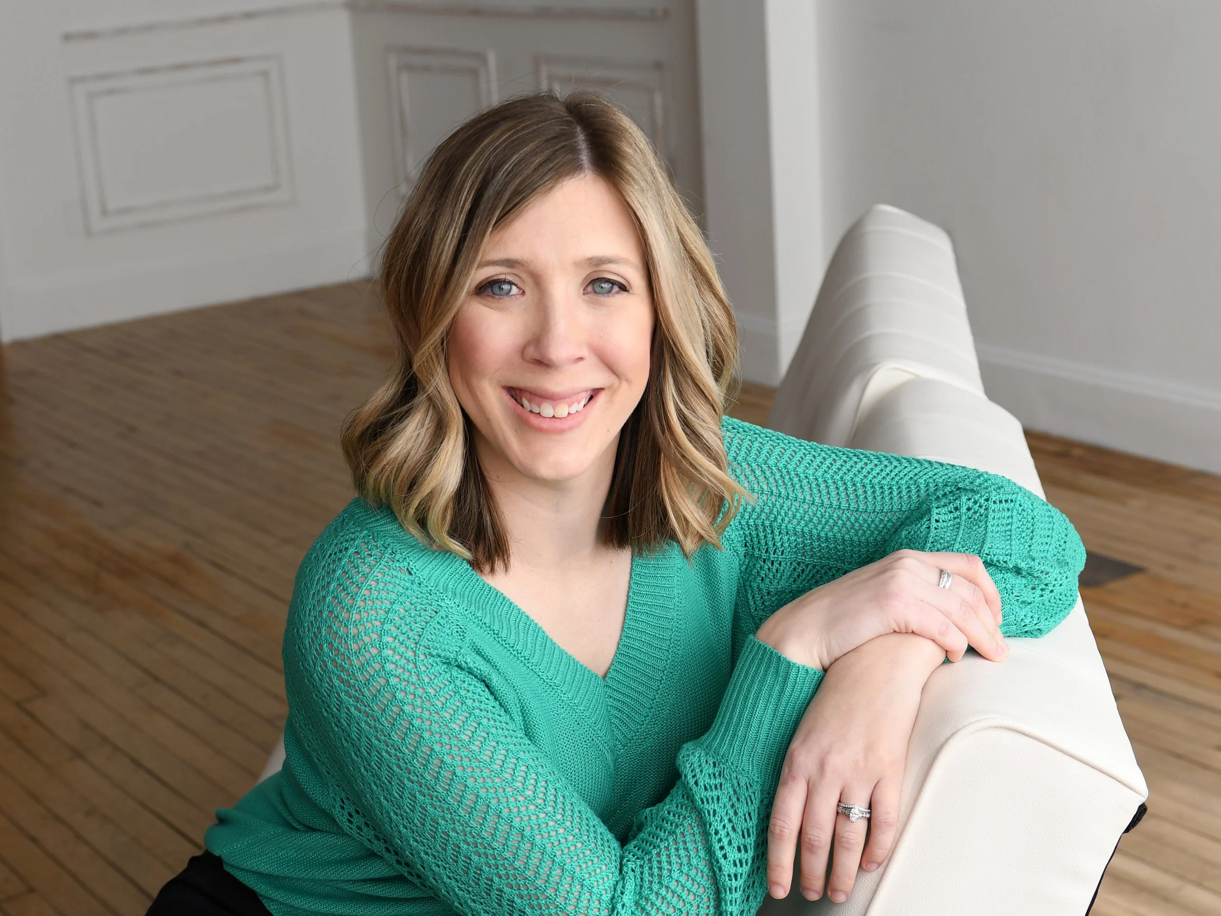 Psychiatry provider in teal shirt sitting on white couch