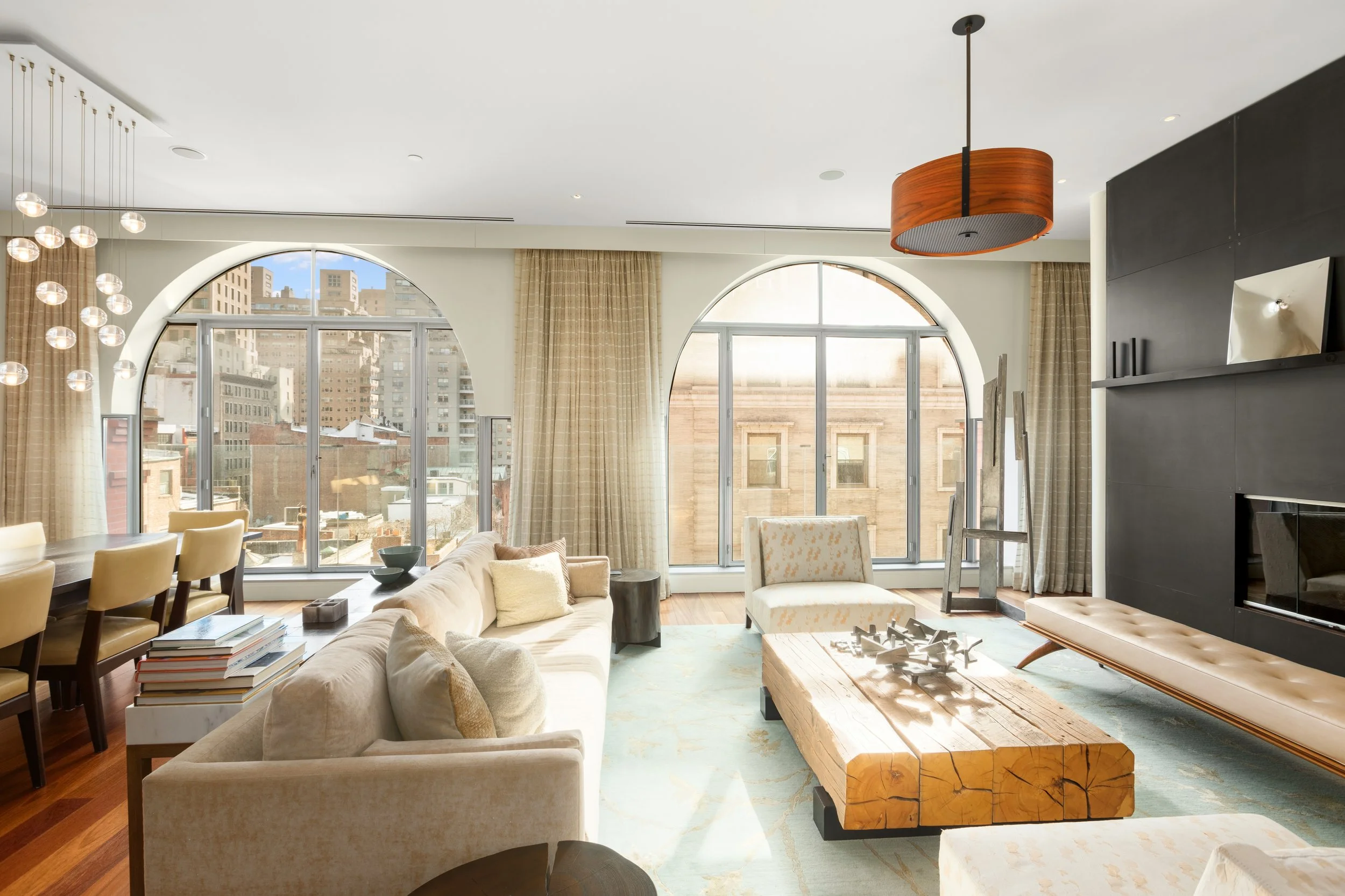 Bright living room with large arched windows, cream sofa, wooden coffee table, and modern decor.