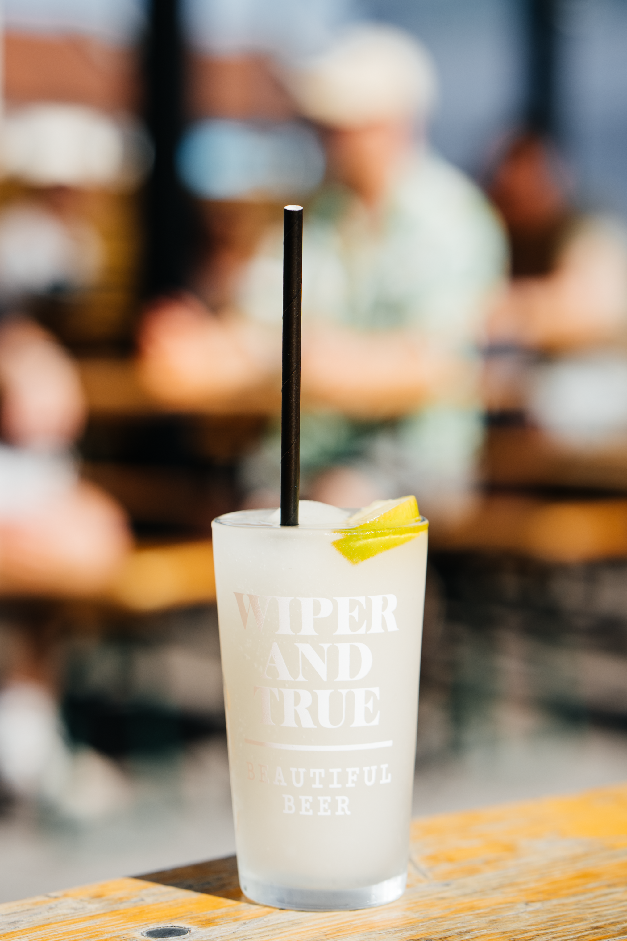 Close-up of a frozen margarita in a tall glass with lemon slices and a straw, in the beer garden of Wiper & True Barrel Store, Bristol