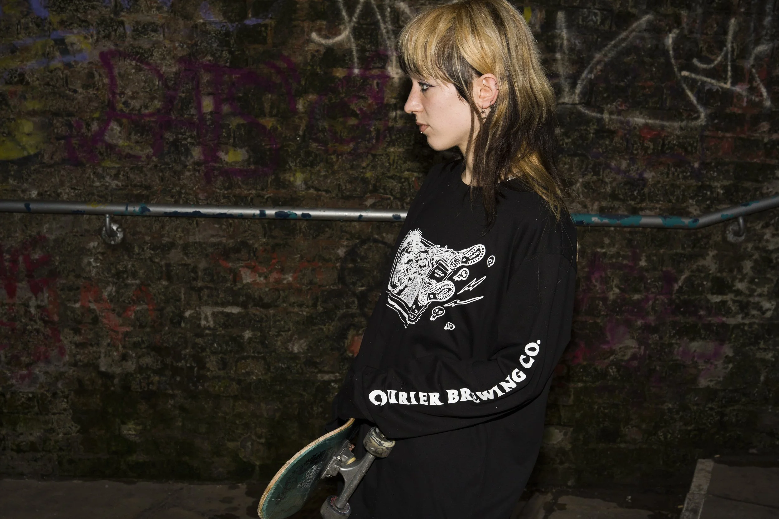 Alice, a skateboarder, wearing long sleeve Courier Brewing Co t-shirt for a merch shoot in Manchester, UK