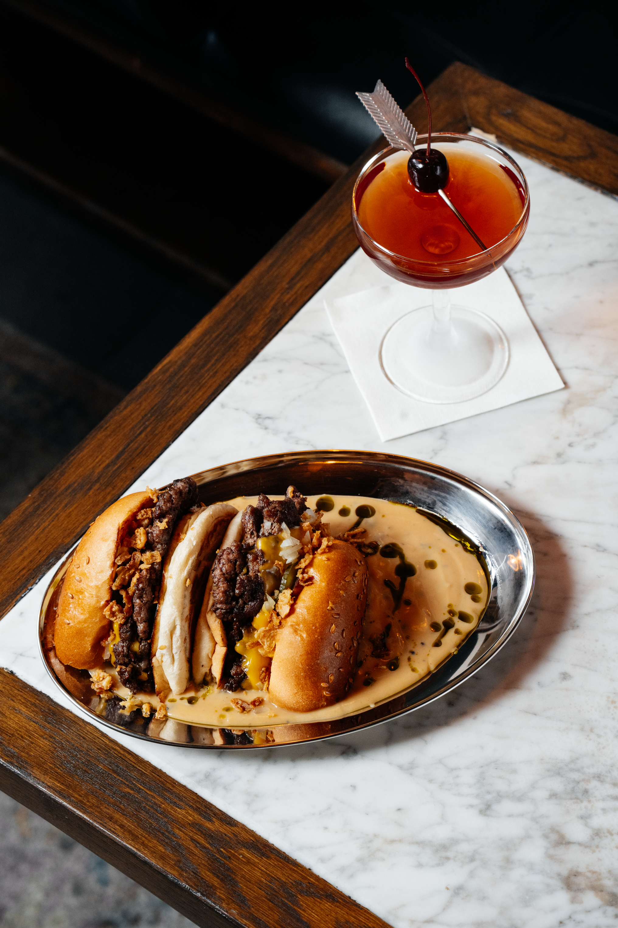 Red cocktail next to a smash burger at at Filthy XIII, Bristol