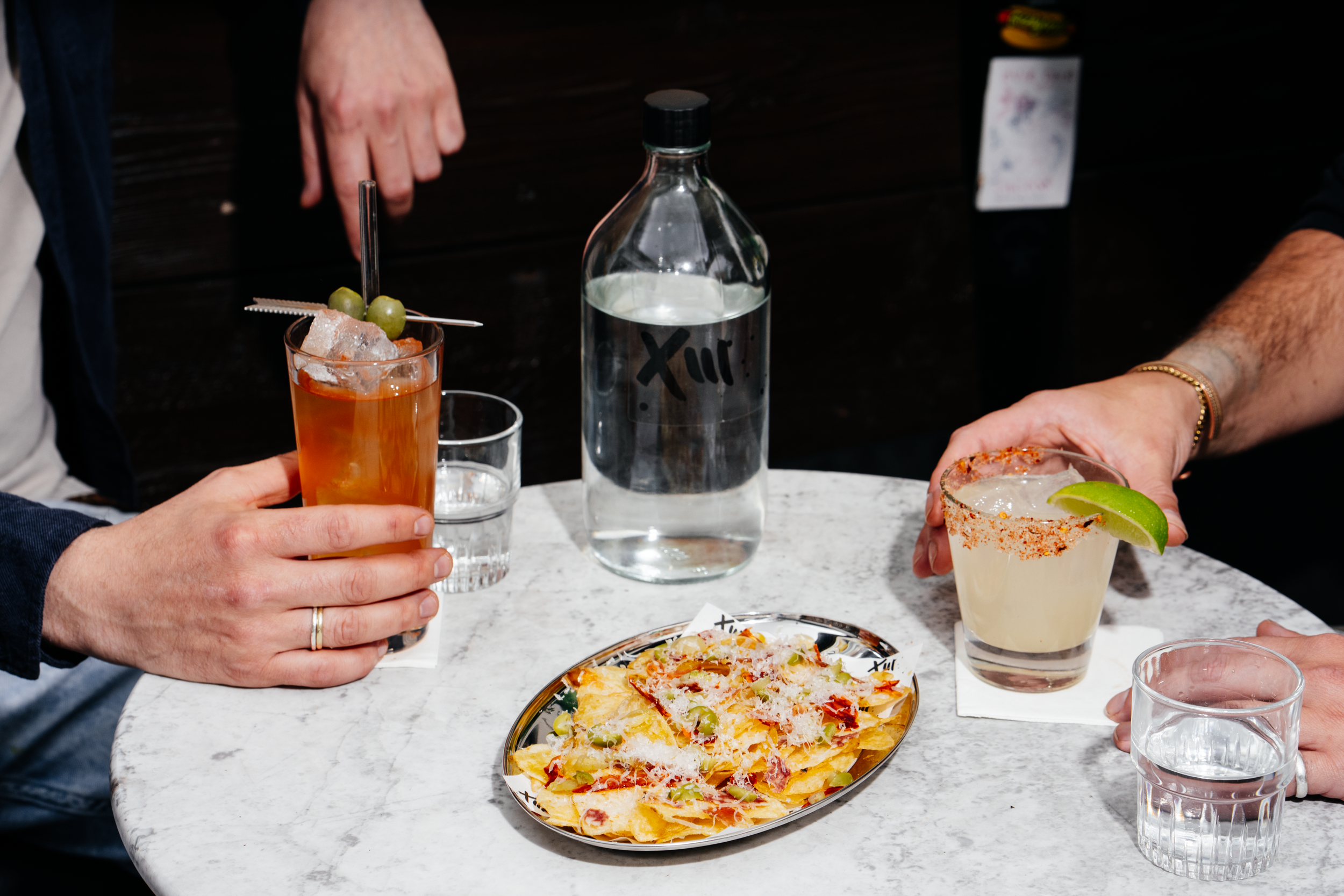 People enjoying two cocktails and some nachos in the Filthy XIII beer garden, Bristol
