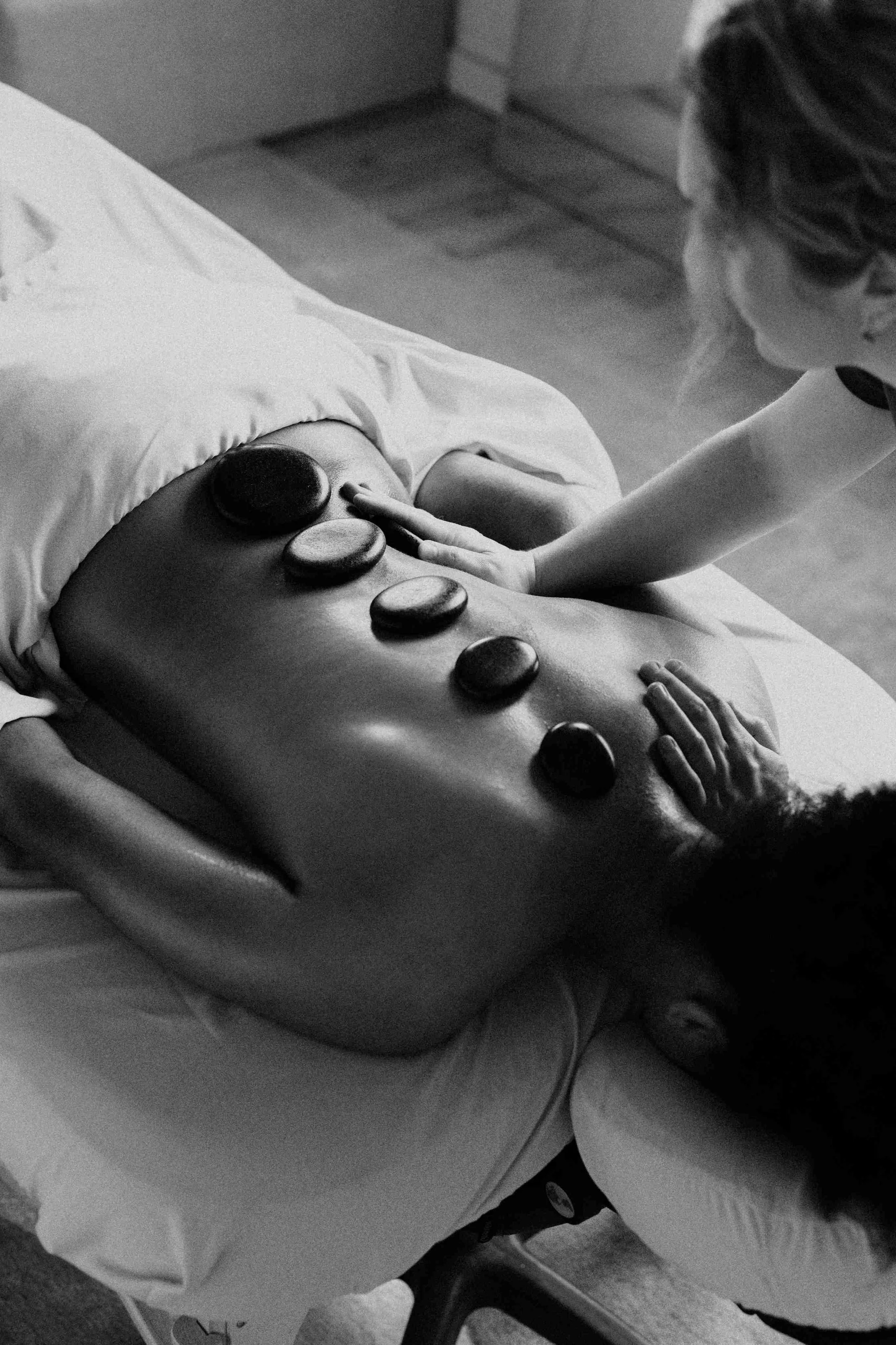 kaitlin lane giving one of her clients a registered massage therapy treatment with hot stones-bordered