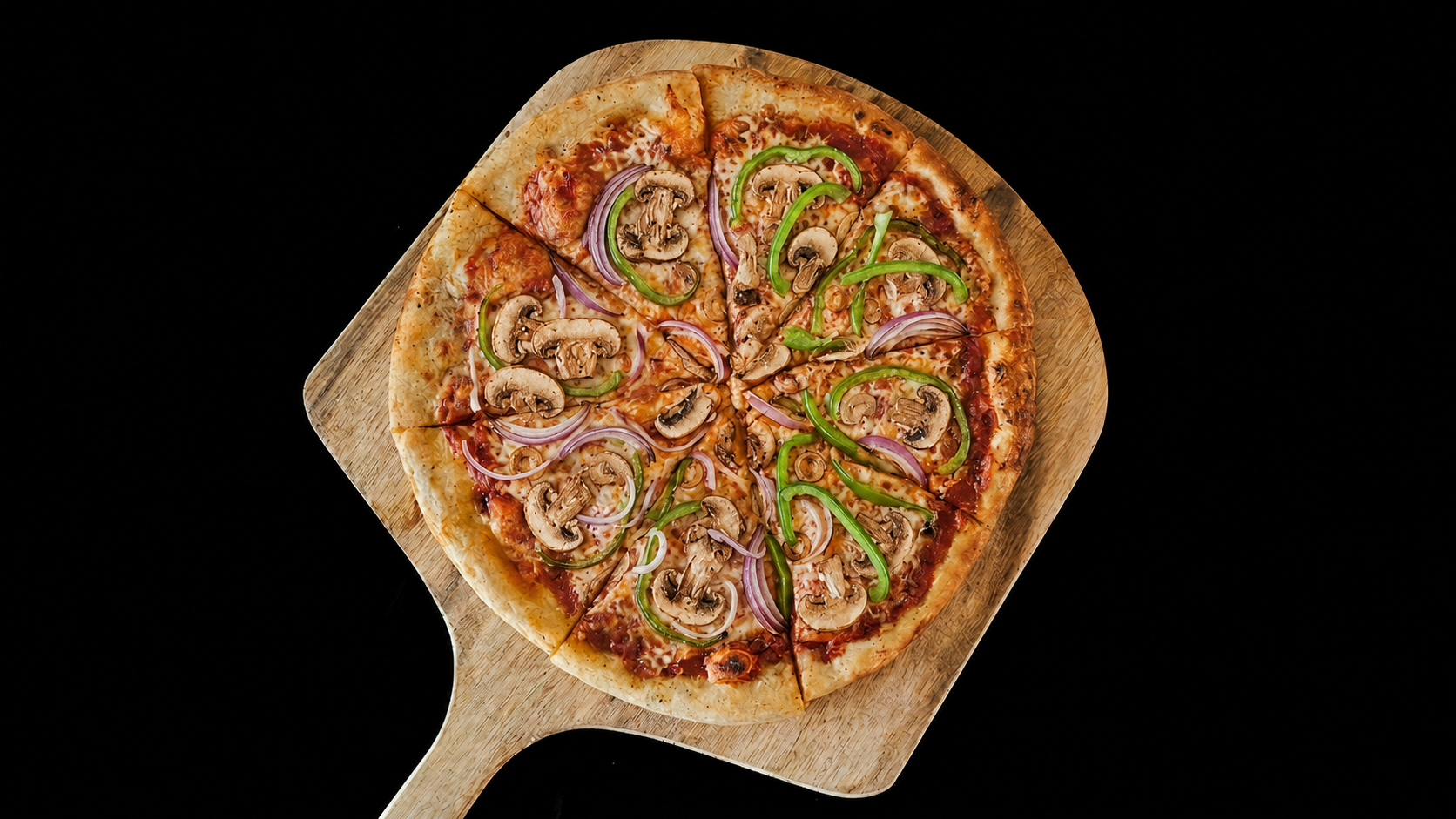 Pizza with mushrooms, black olives, green bell peppers, and red onions on a wooden serving board.
