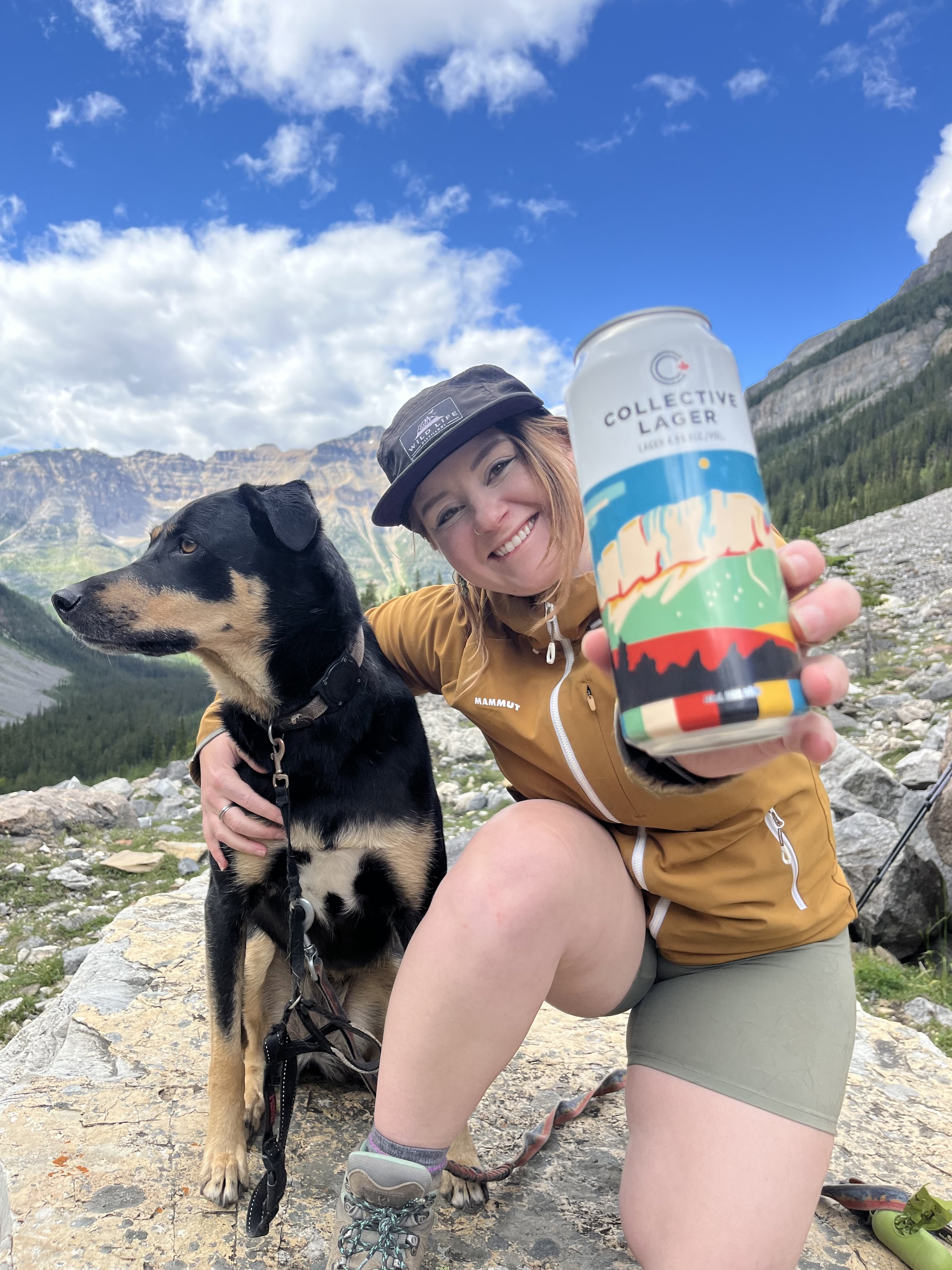 Teenybotanist and her dog on a mountain summit holding a Collective Lager can