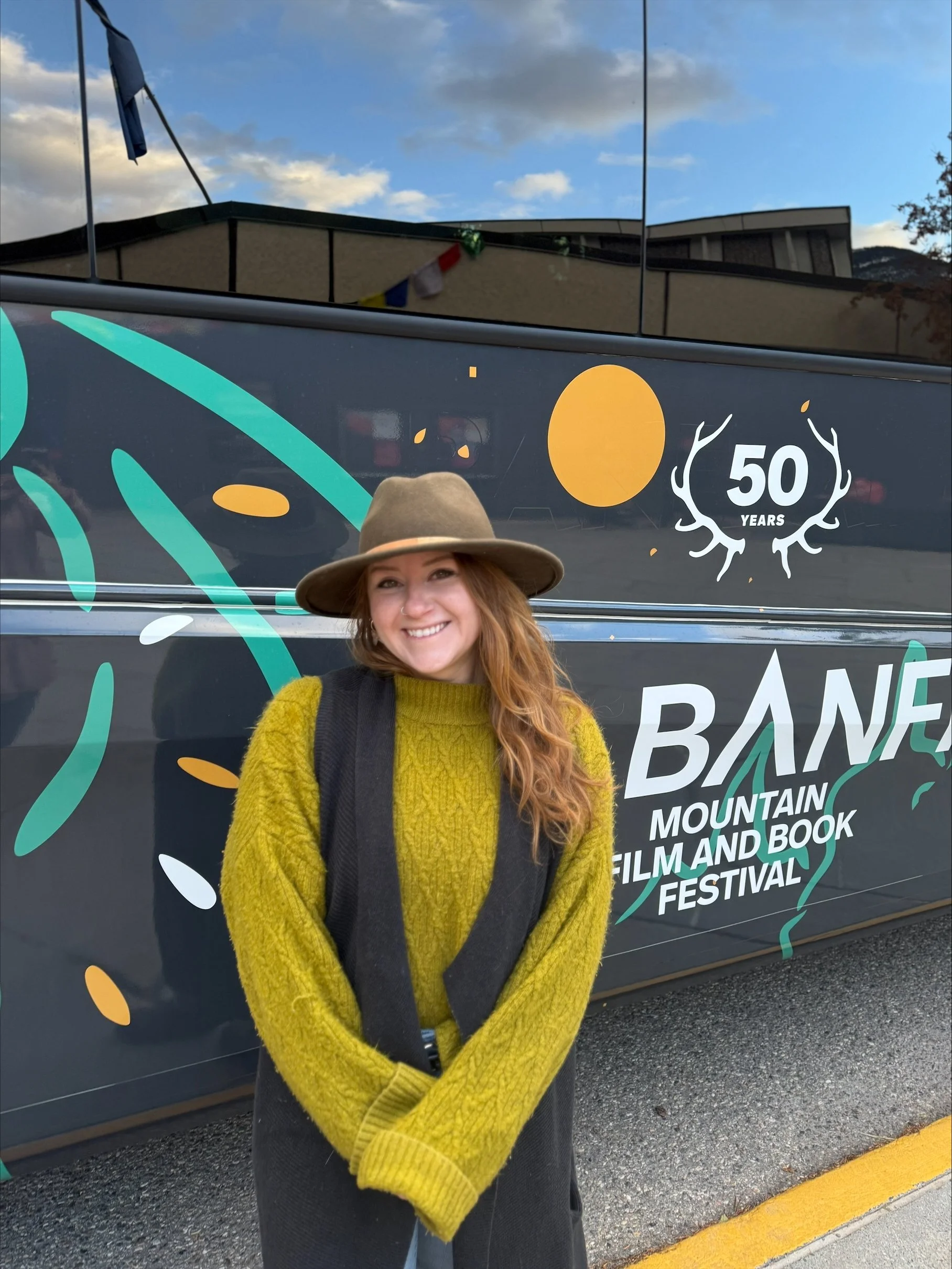 Teenybotanist in front of her Banff Airporter shuttle wrap for the Banff Mountain Film Festival's 50th