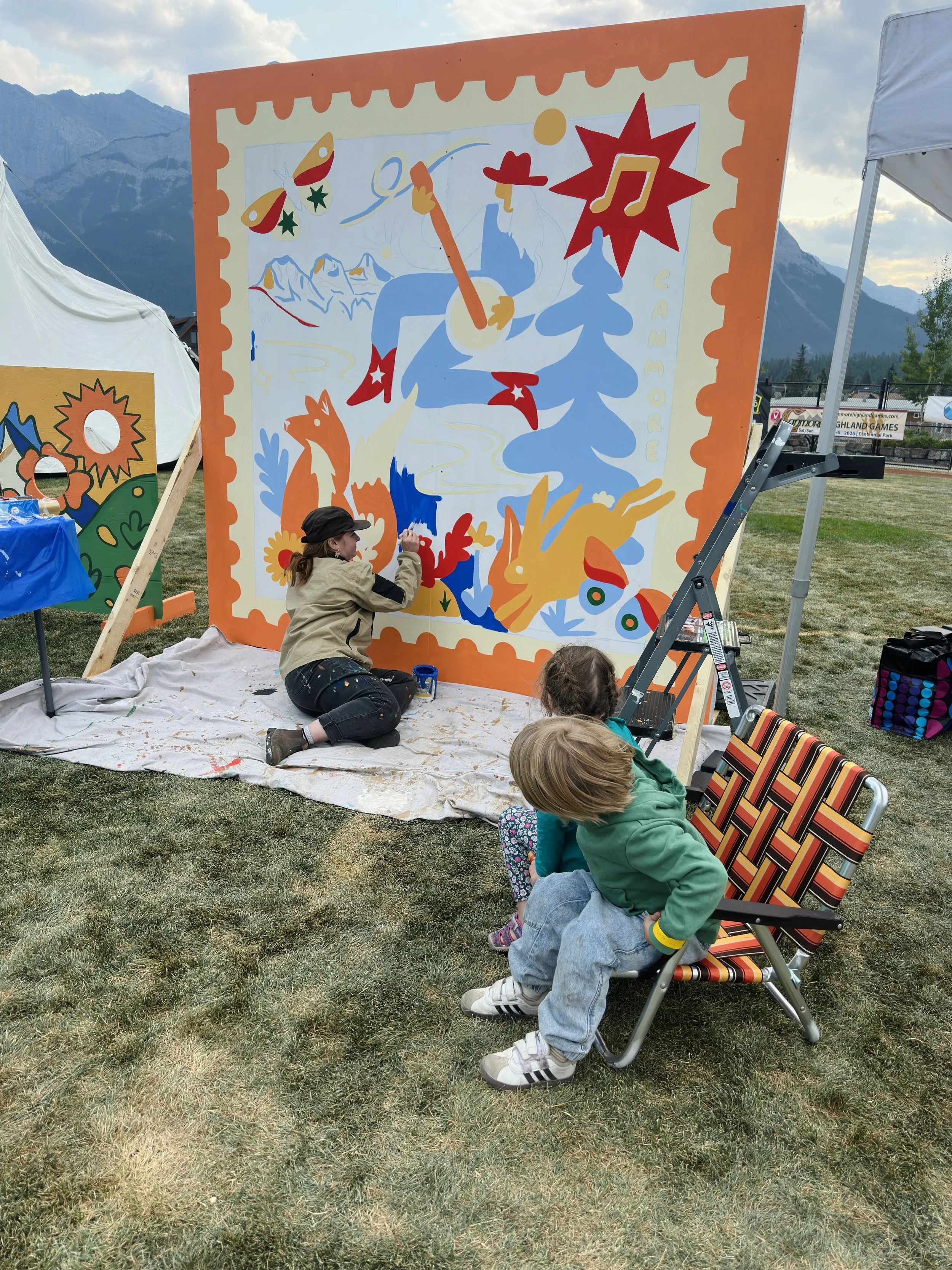 Festival-goers relaxing beside the Out of Office mural