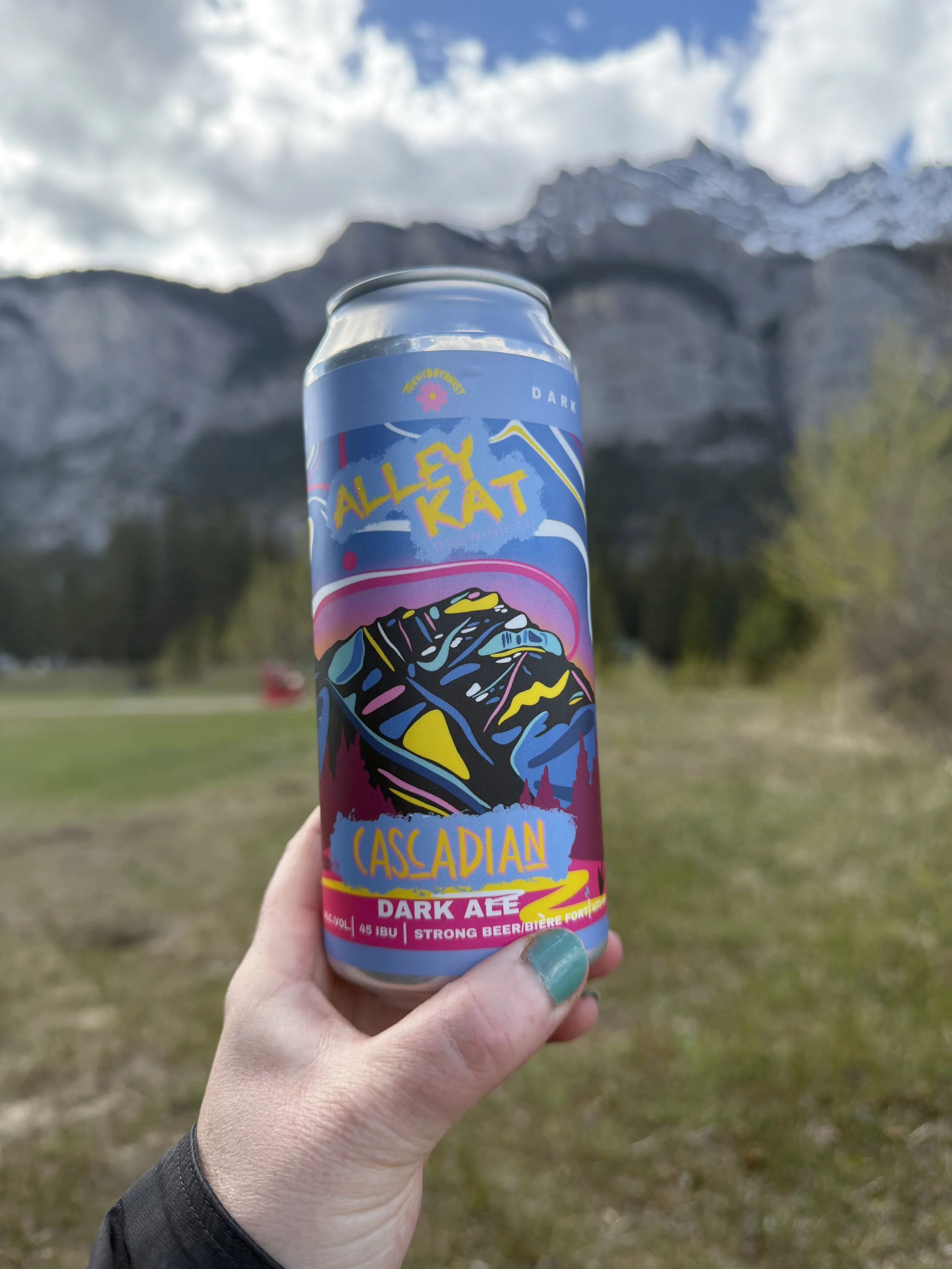 Hand holding an Alley Kat Cascadian Dark Ale can in the mountains