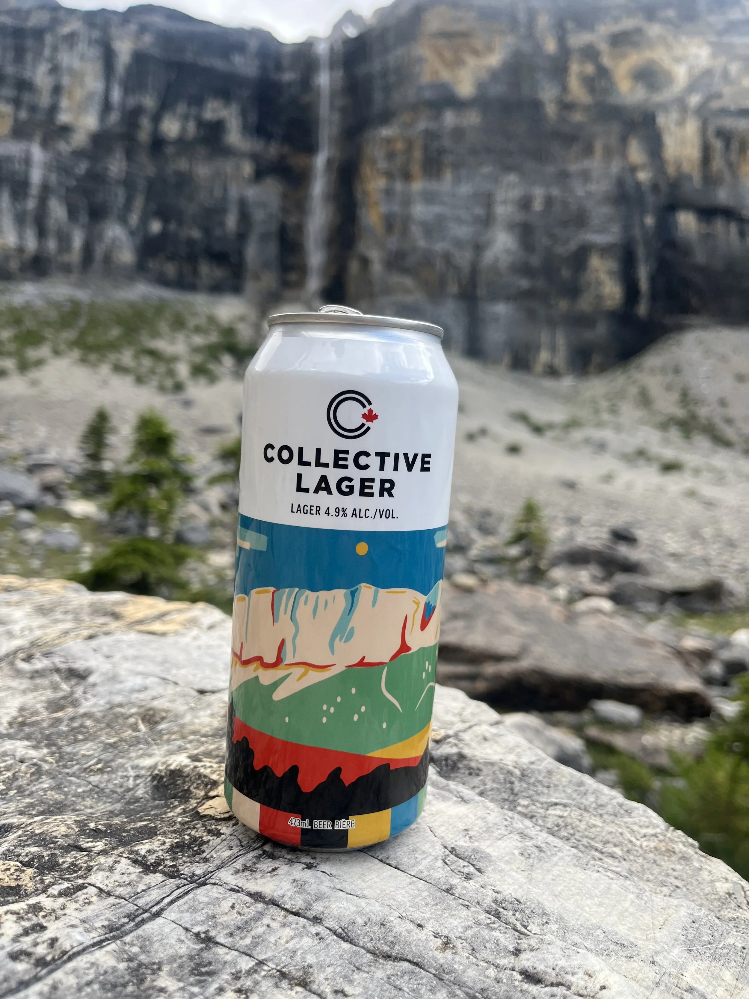 Collective Lager can on a rock below Rocky Mountain cliffs
