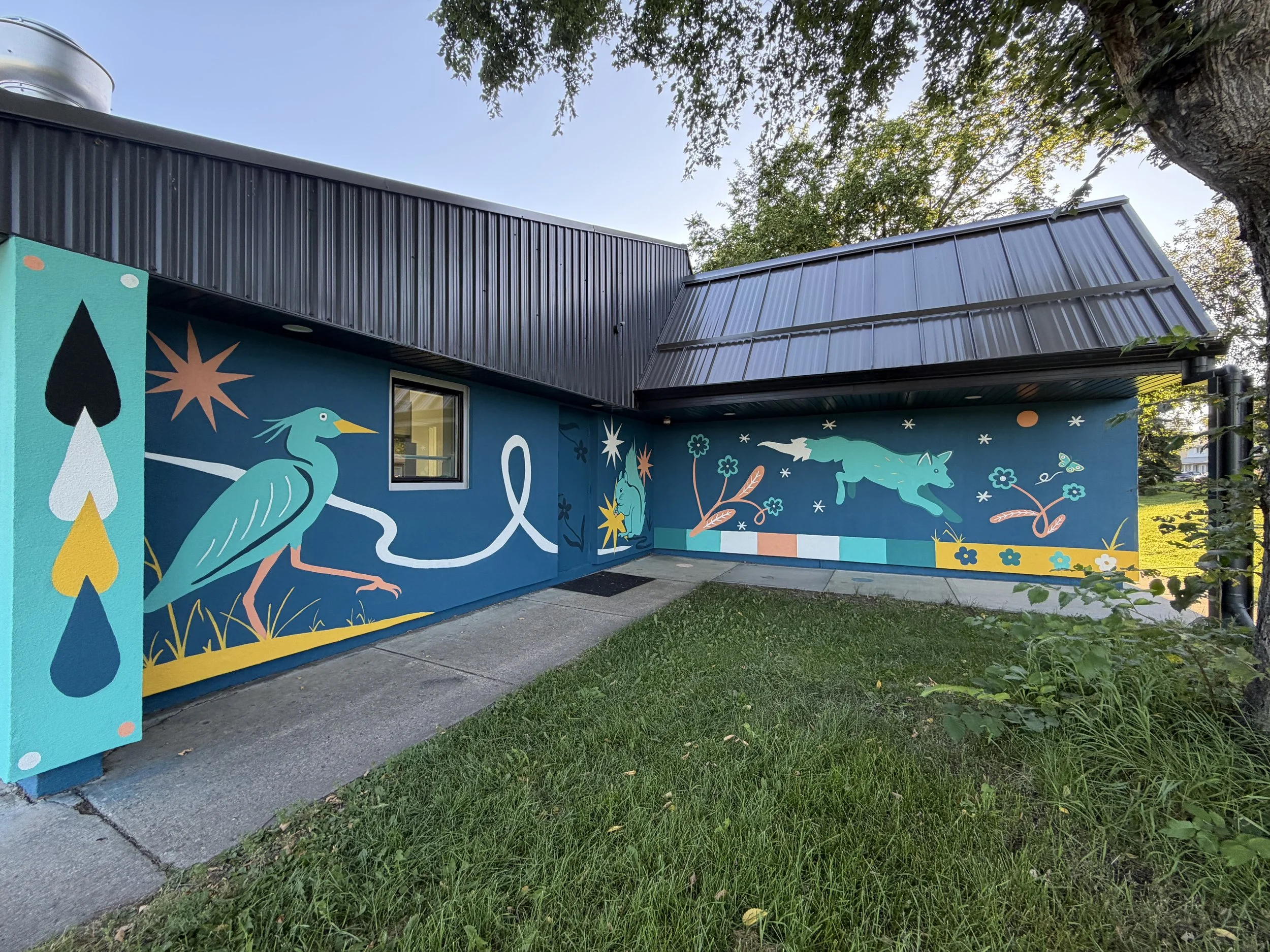 Corner of the Aspen Gardens building covered in murals