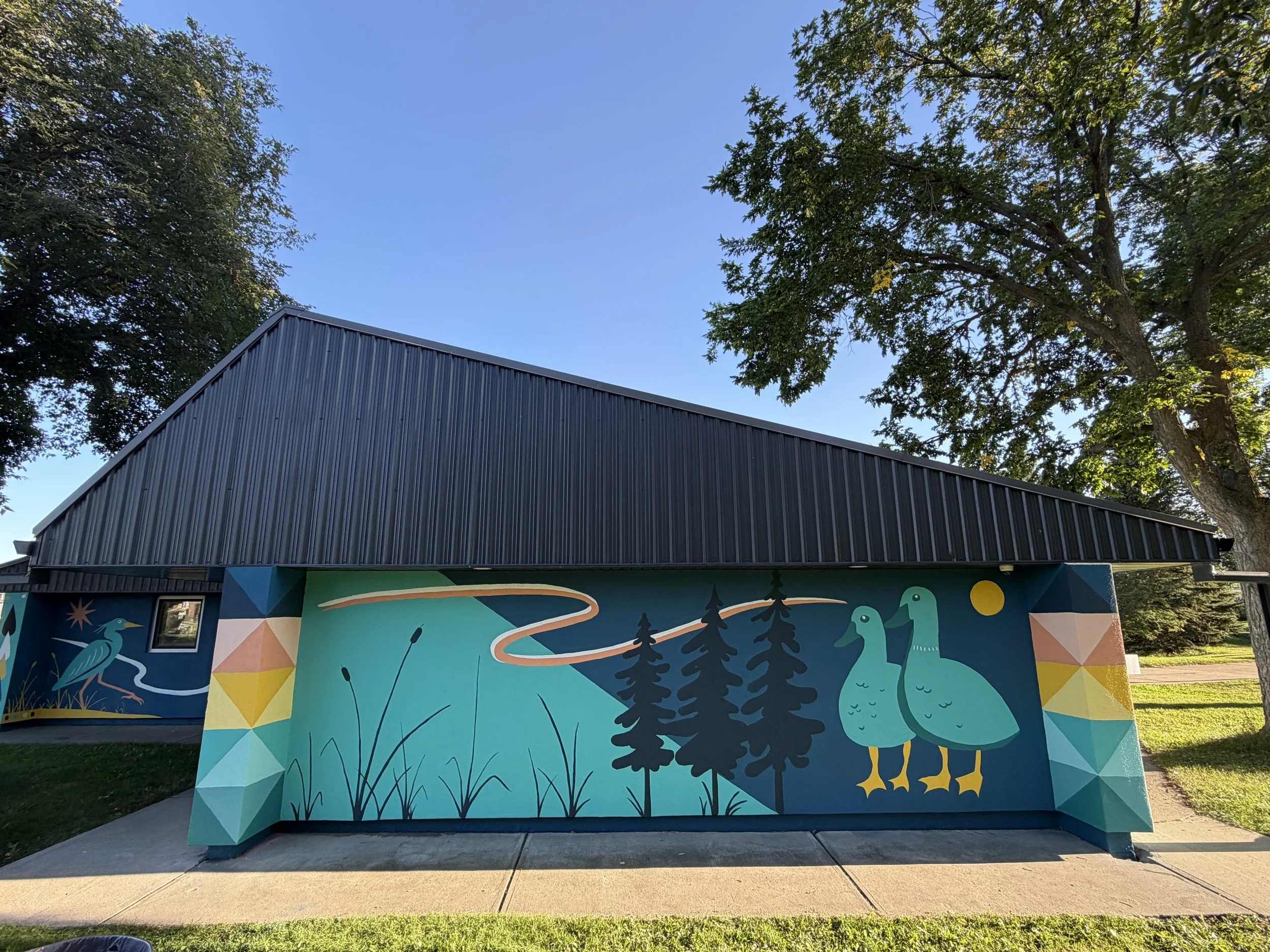 Aspen Gardens building murals framed by trees