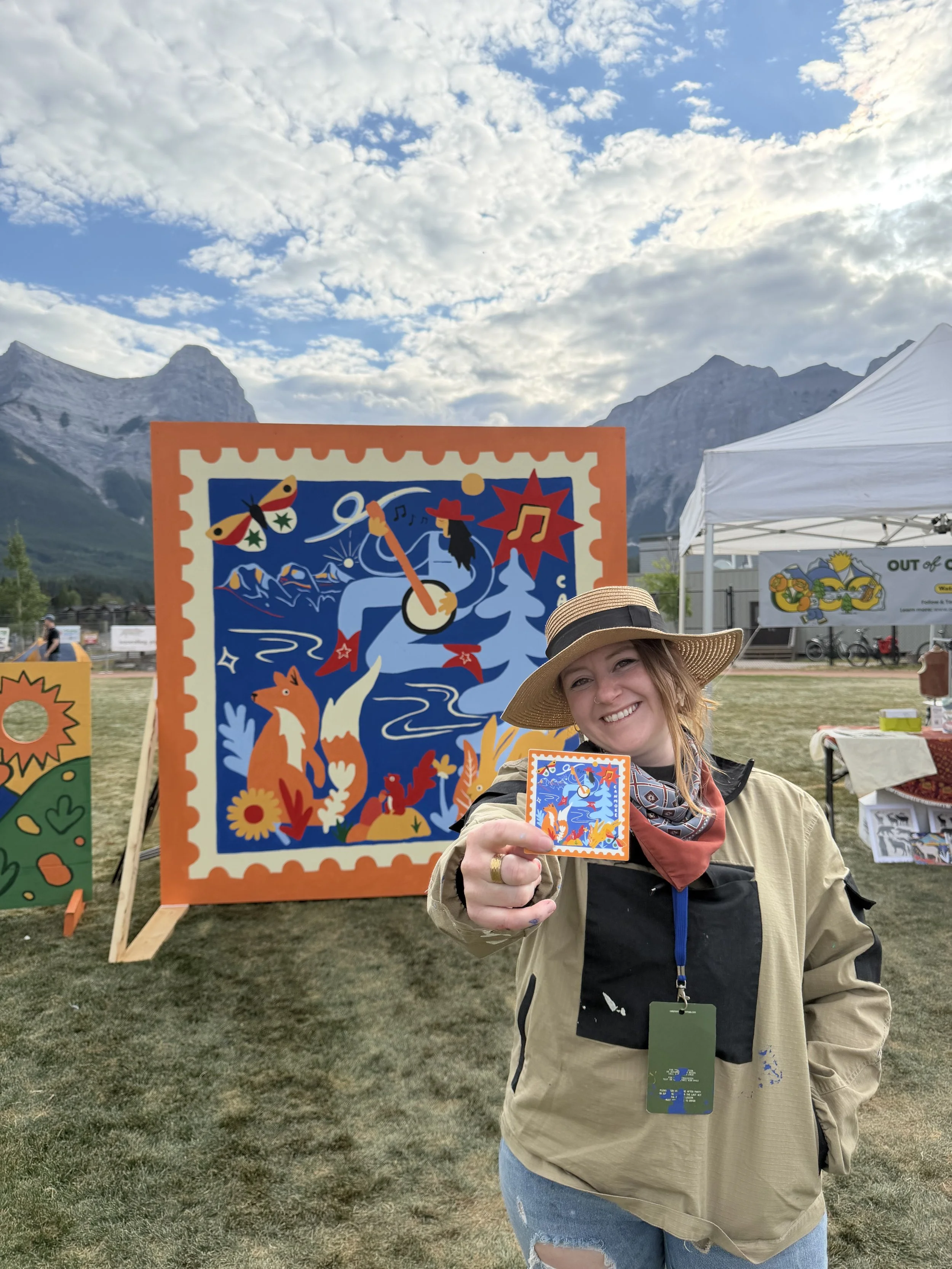 Festival visitor holding a sticker in front of the Out of Office mural