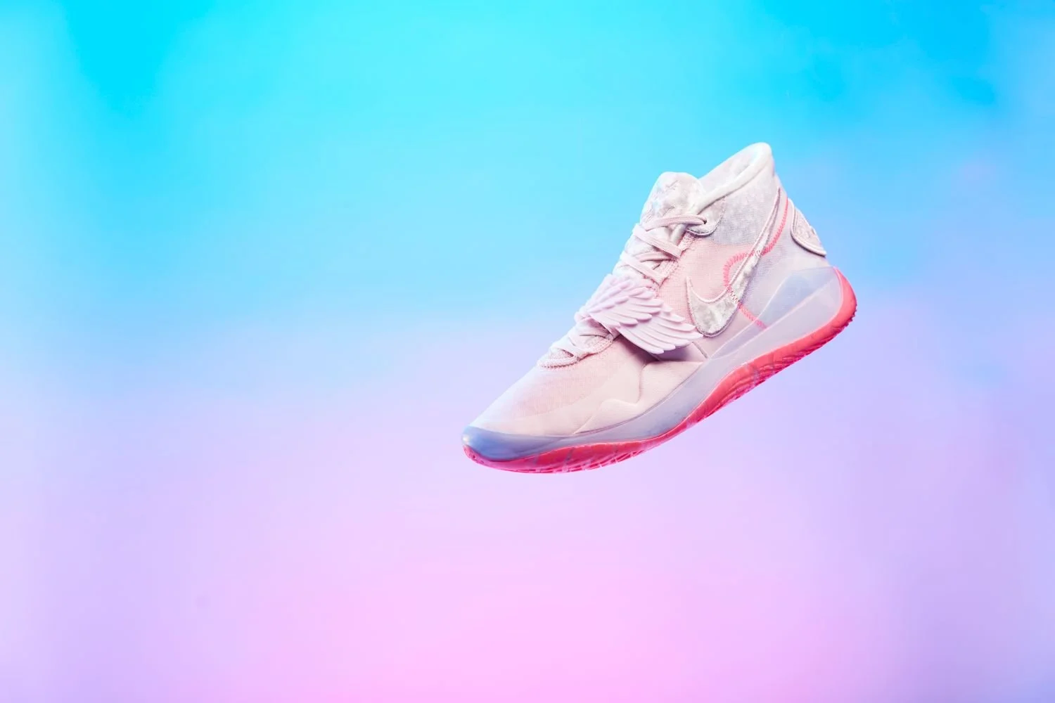 A pink running shoe with wing and cloud design on a pastel gradient background.