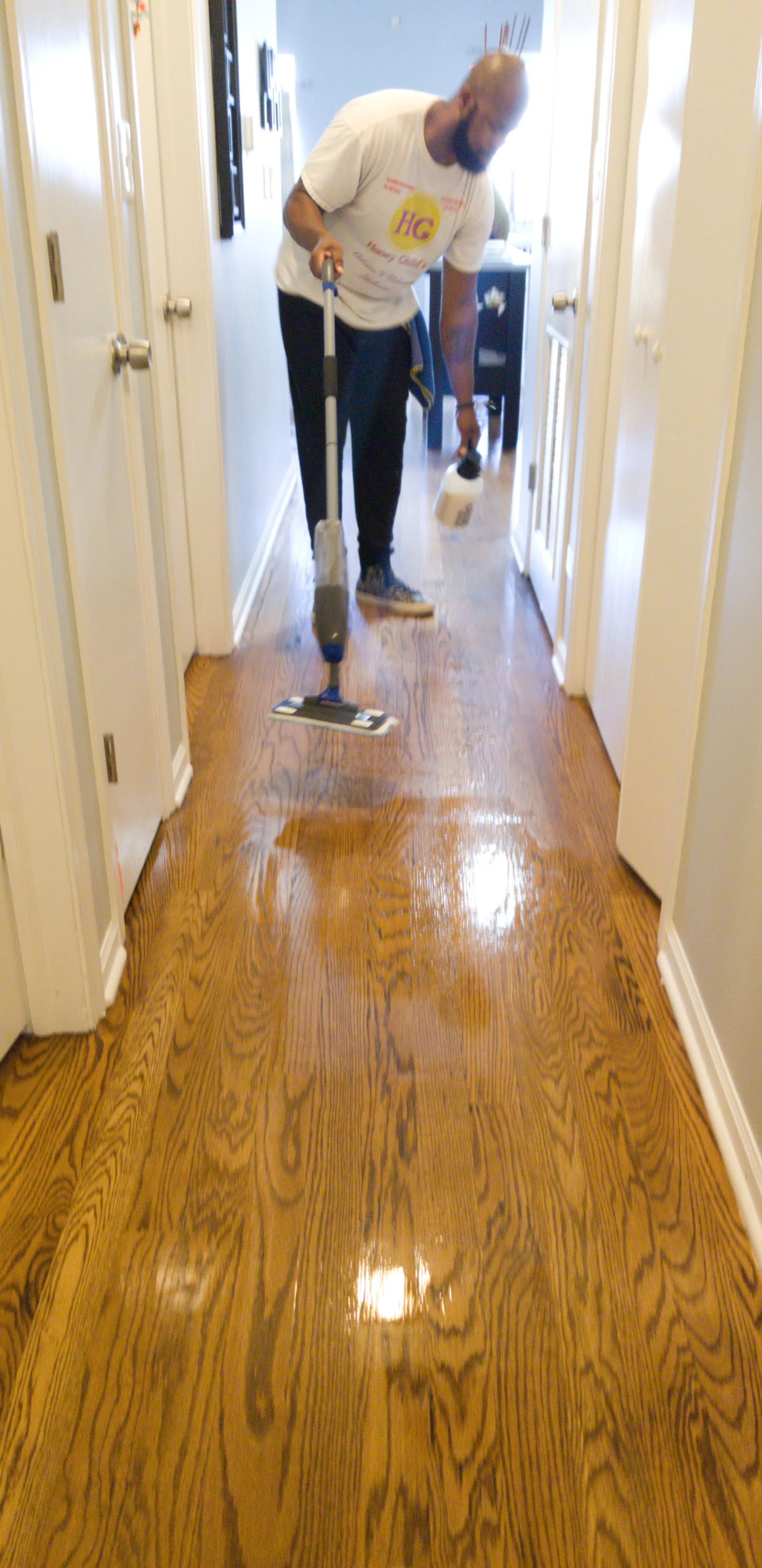 Man cleaning wooden floor with a mop in a hallway.