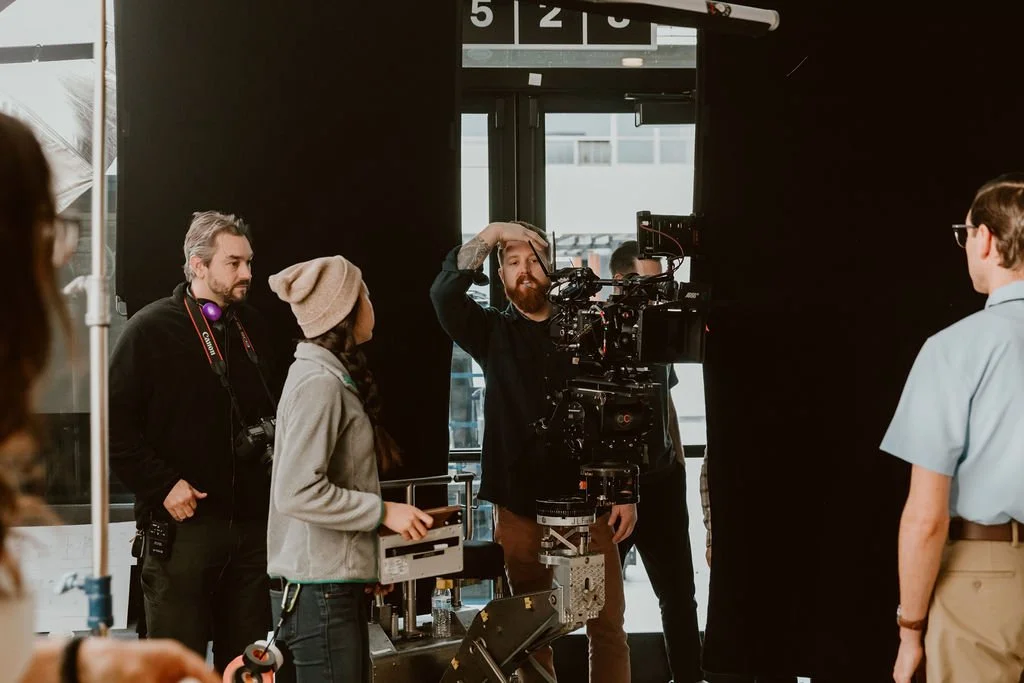 Film crew setting up equipment with a camera focused on a man in uniform during a filming session.
