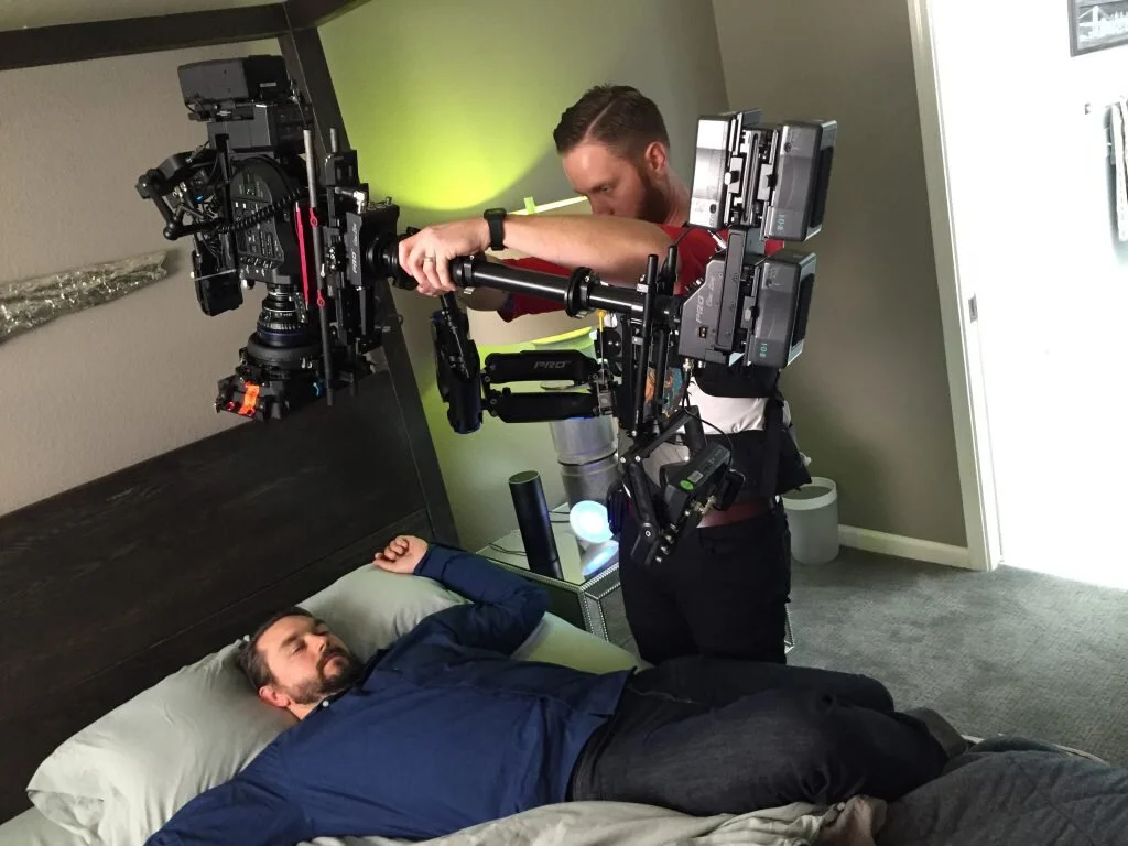 A man lying in bed with a camera rig filming or photographing him