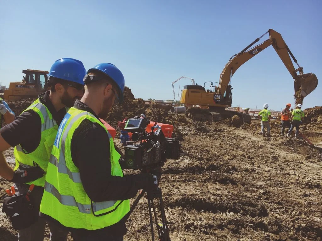 Construction site with workers and excavation equipment under clear blue sky.